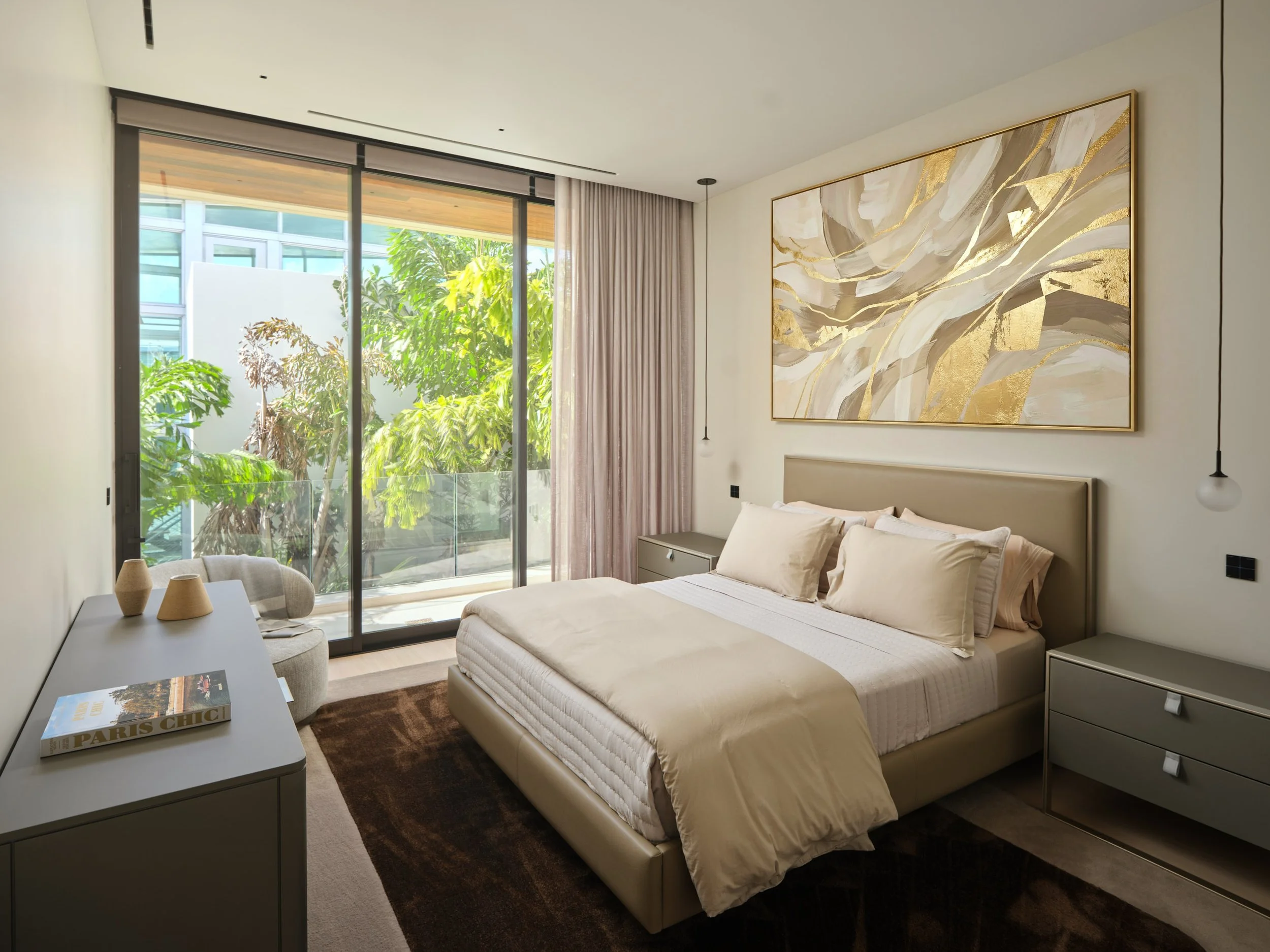 Architectural photograph of a modern bedroom with balcony views, neutral palette, and large abstract gold artwork inside a Venetian Islands luxury residence in Miami. Captured by Miami and Los Angeles-based architectural and travel photographer Chris