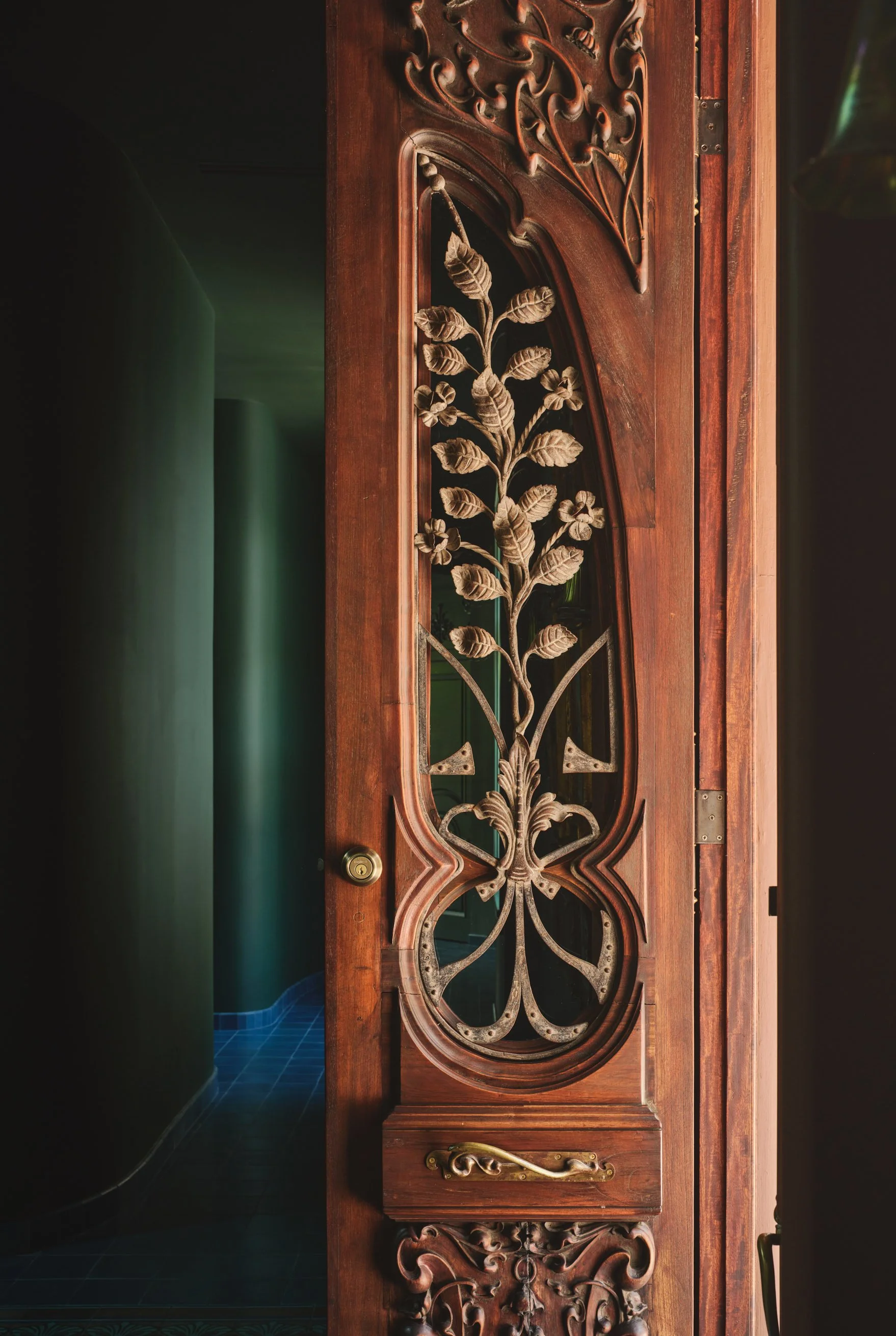 Architectural detail of an ornate Art Nouveau front door with carved wood, floral metalwork, and dramatic directional light in a custom Miami residence. Captured by Miami and Los Angeles-based architectural and travel photographer Christian Santiago.