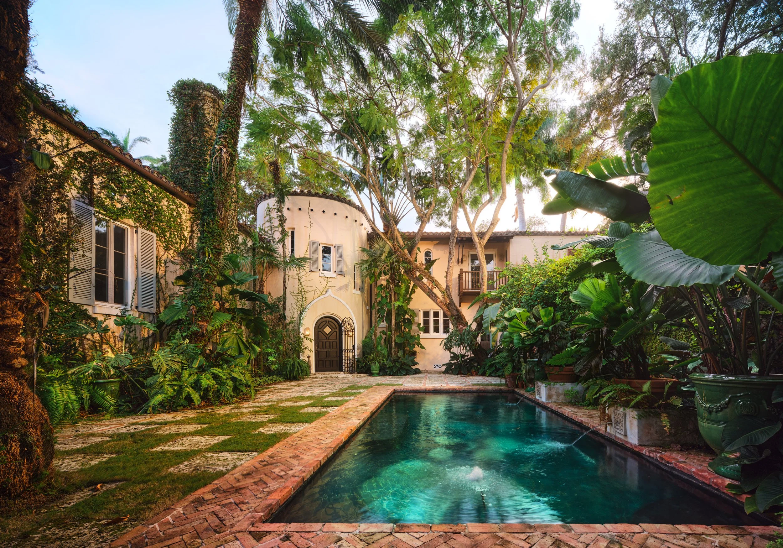 Architectural photograph of Villa Serenita’s ivy-clad Mediterranean Revival façade, arched entry, and brick-lined pool courtyard surrounded by lush tropical gardens. Coconut Grove, Miami. Captured by Miami and Los Angeles-based architectural and trav