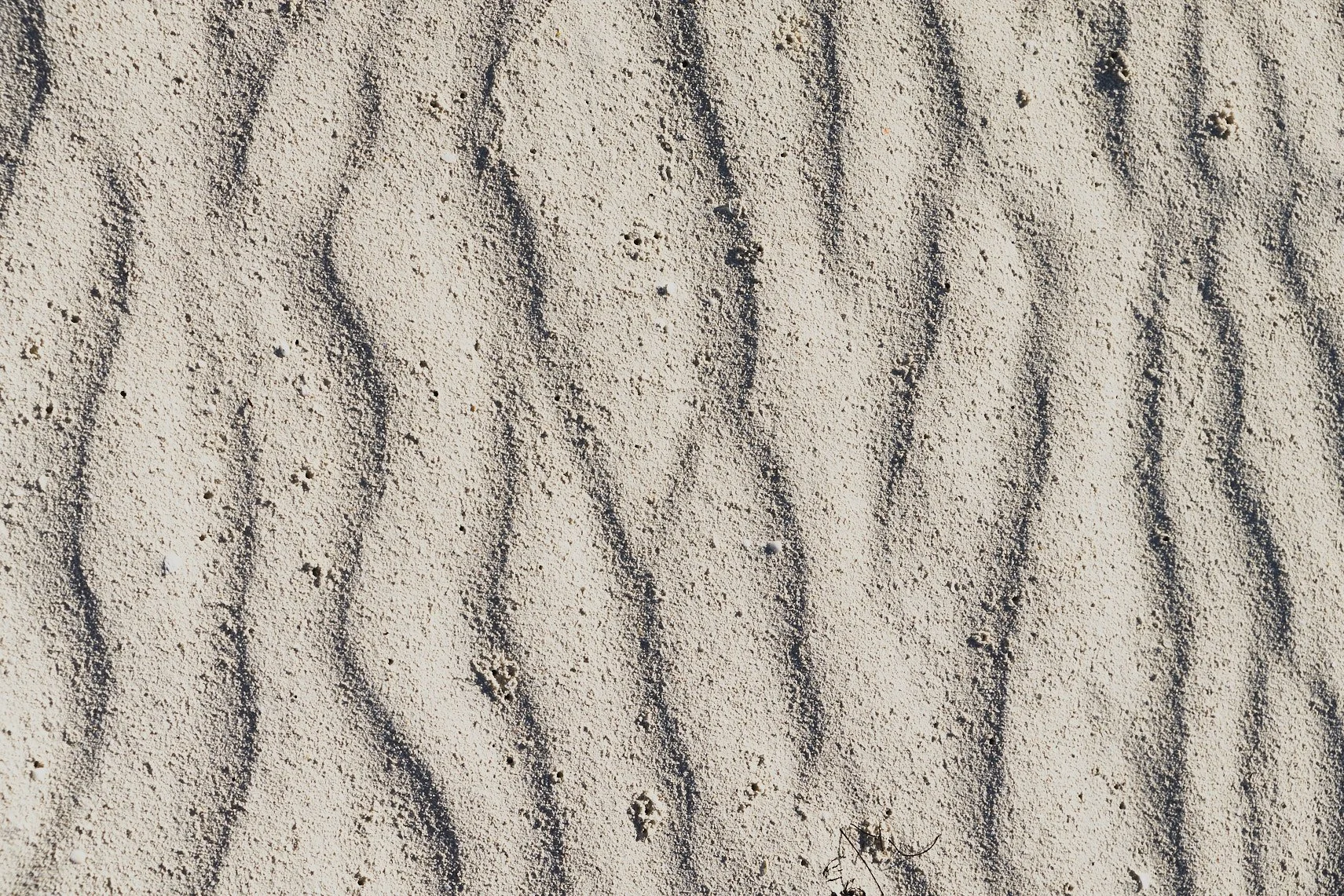 A detailed shot of wavy textures and patterns on a bed of sand with specular sunlight. Captured by Miami Architectural & Travel Photographer Christian Santiago