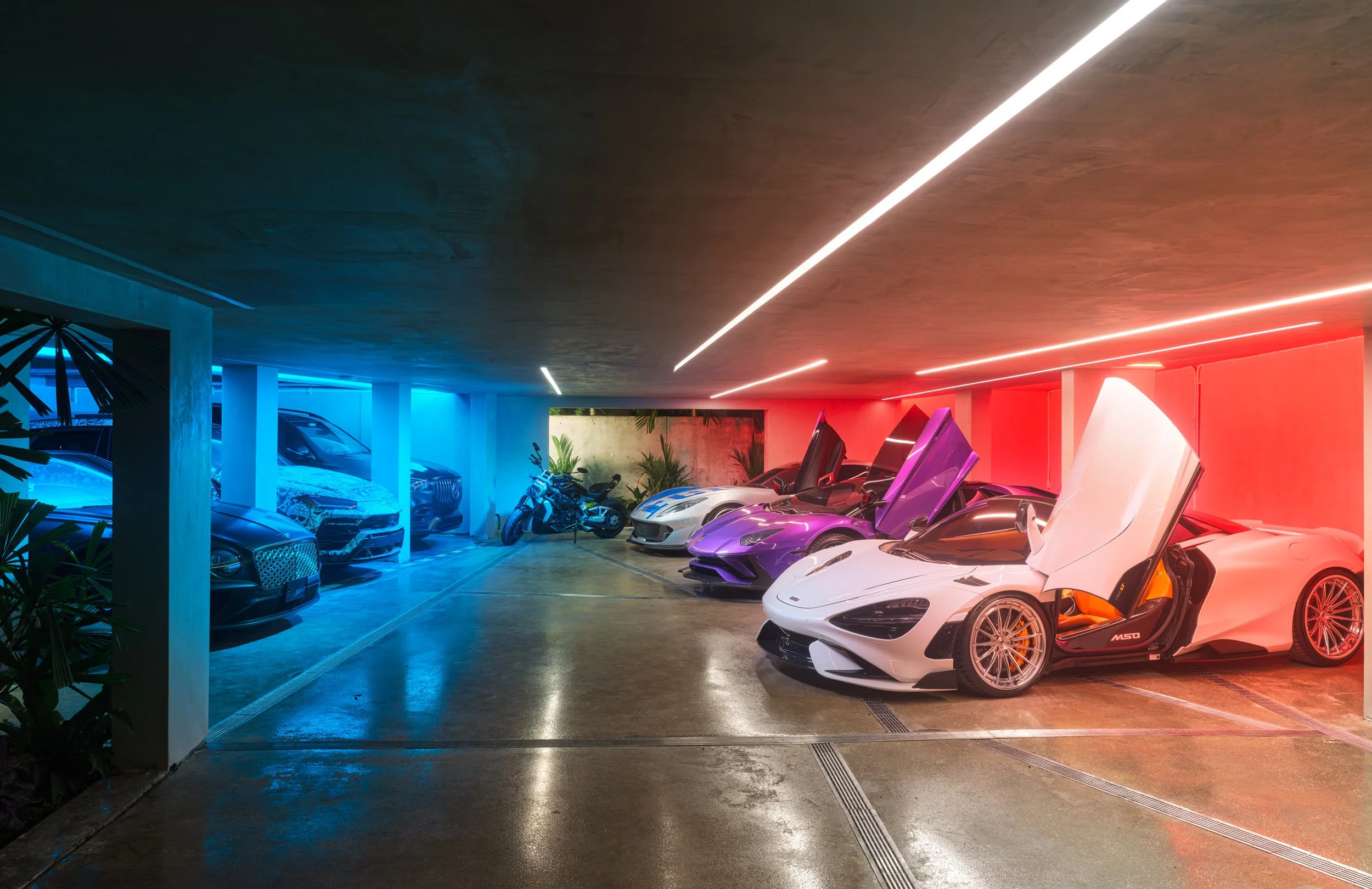 Architectural photograph of a luxury garage with dramatic lighting and supercars inside a Venetian Islands waterfront residence in Miami. Captured by Miami and Los Angeles-based architectural photographer Christian Santiago