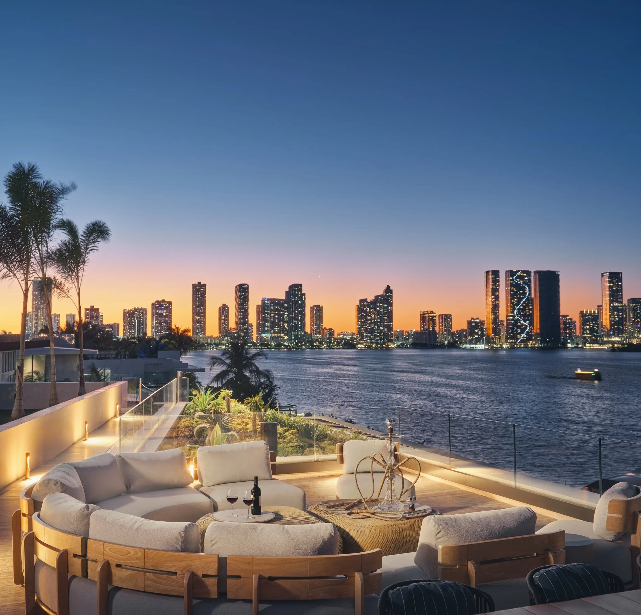 Architectural photograph of a waterfront rooftop terrace at dusk overlooking Biscayne Bay and the illuminated Miami skyline from a Venetian Islands residence. Captured by Miami and Los Angeles-based architectural and travel photographer Christian San