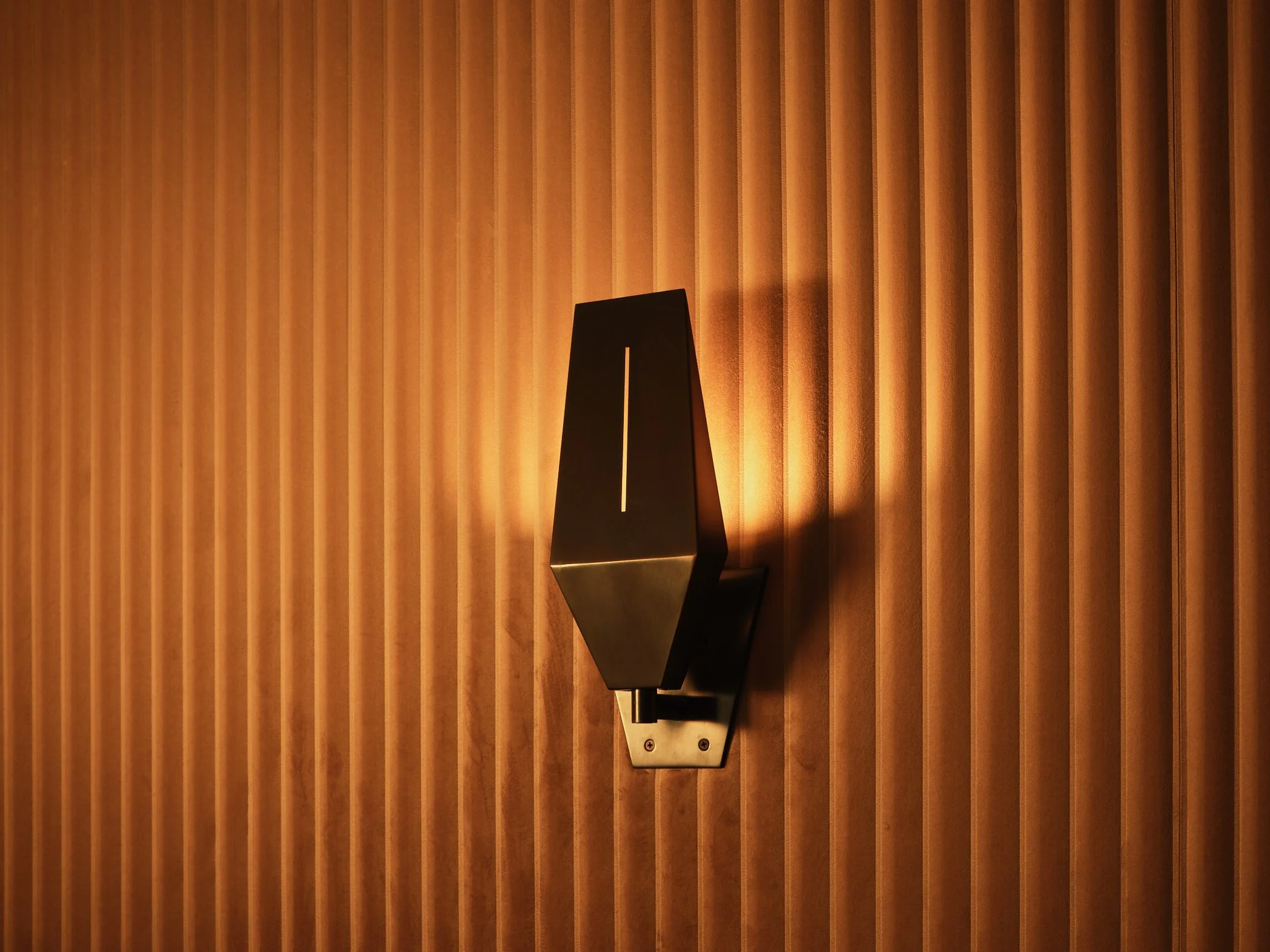 Architectural photograph of a sculptural wall sconce illuminating vertical wood slat paneling inside a luxury home theater in a modern Miami residence. Captured by Miami and Los Angeles-based architectural and travel photographer Christian Santiago.