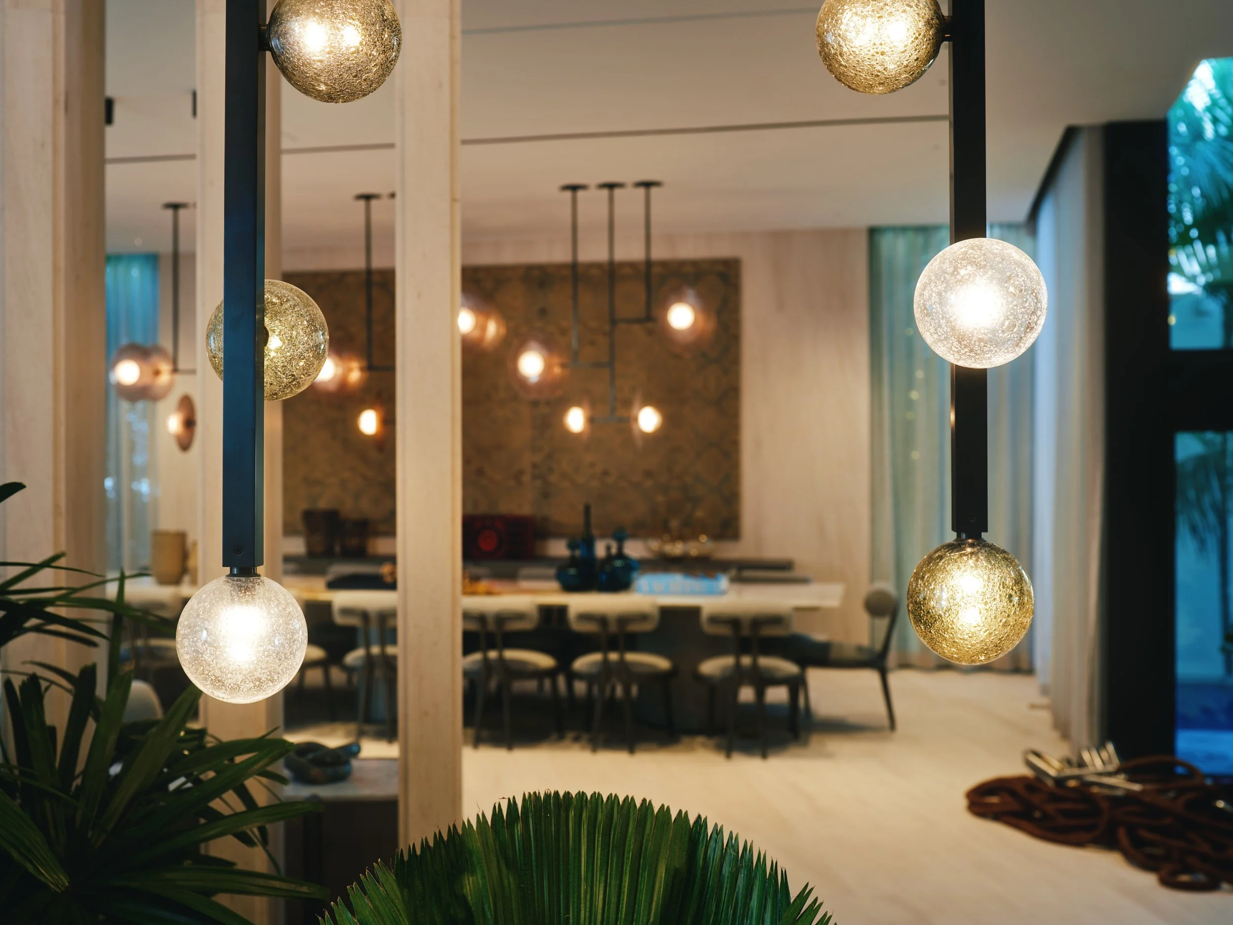 Architectural photograph of modern glass globe pendant lights illuminating a luxury dining room interior in a Venetian Islands residence in Miami. Captured by Miami and Los Angeles-based architectural and travel photographer Christian Santiago.