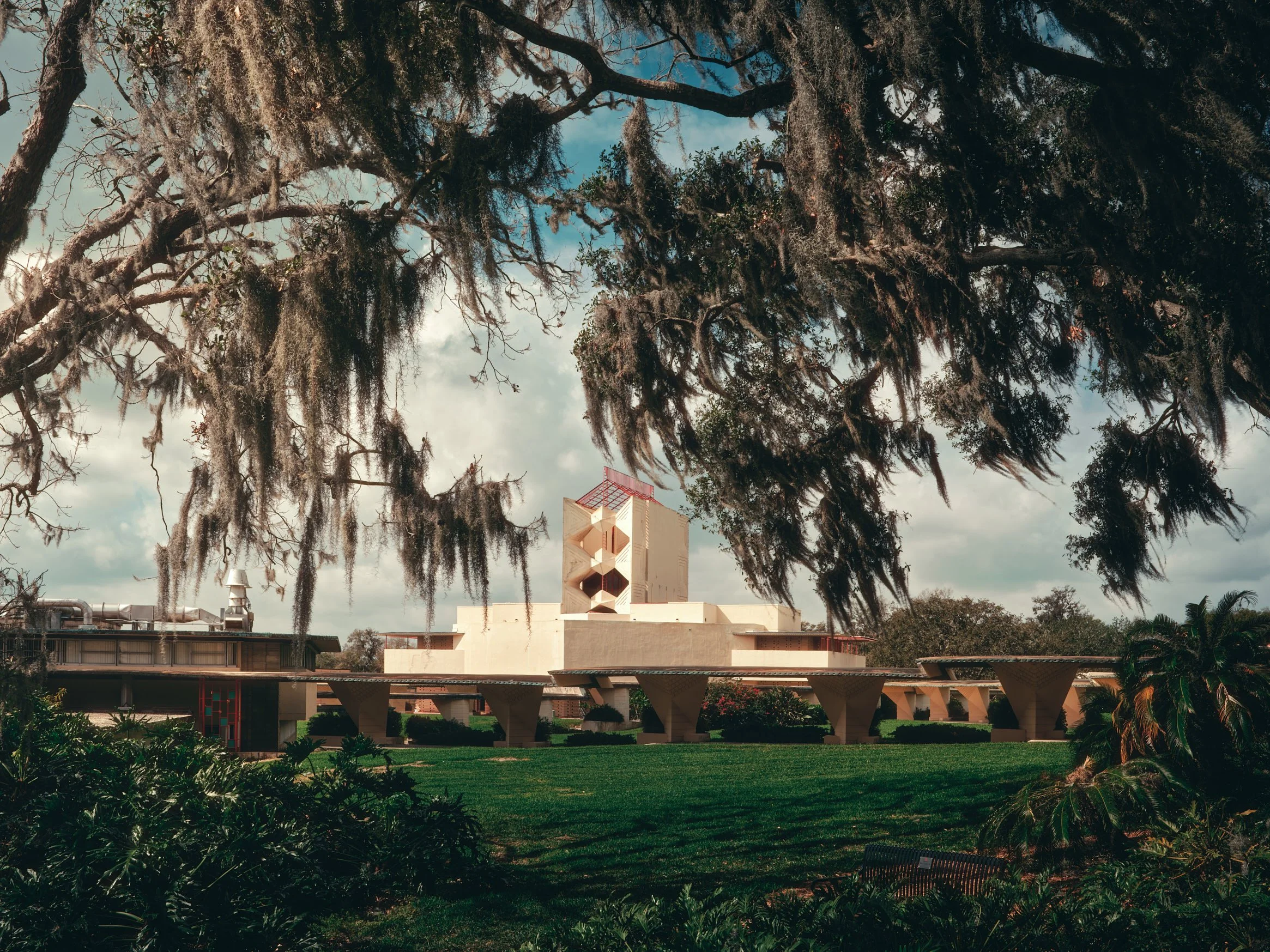 Architectural photograph of the Annie Pfeiffer Chapel at Florida Southern College in Lakeland, Florida, framed by sweeping Spanish moss-draped oak trees — one of the largest collections of Frank Lloyd Wright architecture in the world, captured in war