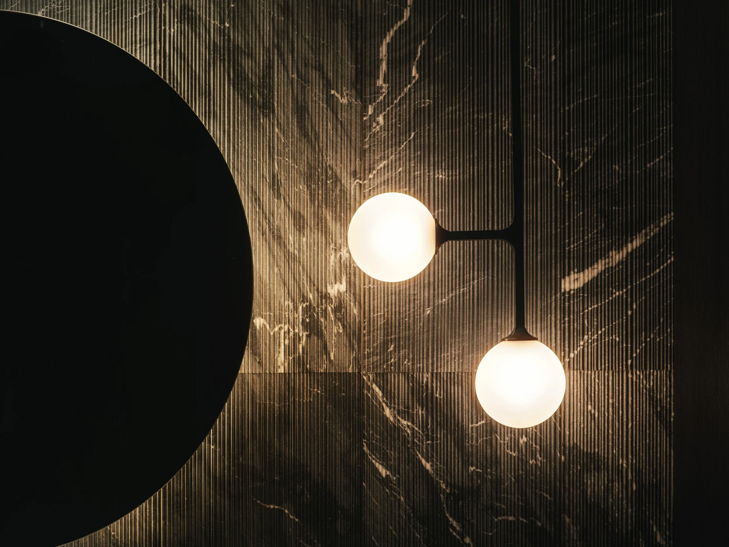 Architectural photograph of sculptural wall lighting and stone texture detail in a luxury powder room inside a Venetian Islands waterfront residence in Miami. Captured by Miami and Los Angeles-based architectural photographer Christian Santiago