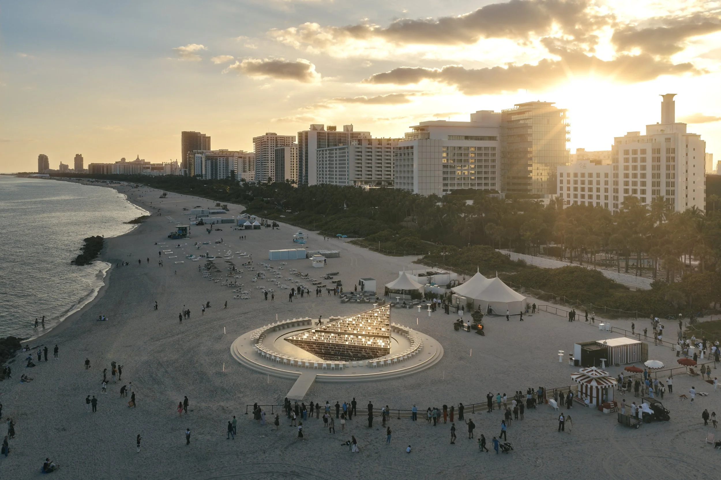 Architectural photograph of Es Devlin’s Library of Us public art installation at Faena Miami Beach during Art Basel Miami Beach, captured at golden hour with the circular structure embedded into the beachfront landscape. The wide perspective highligh