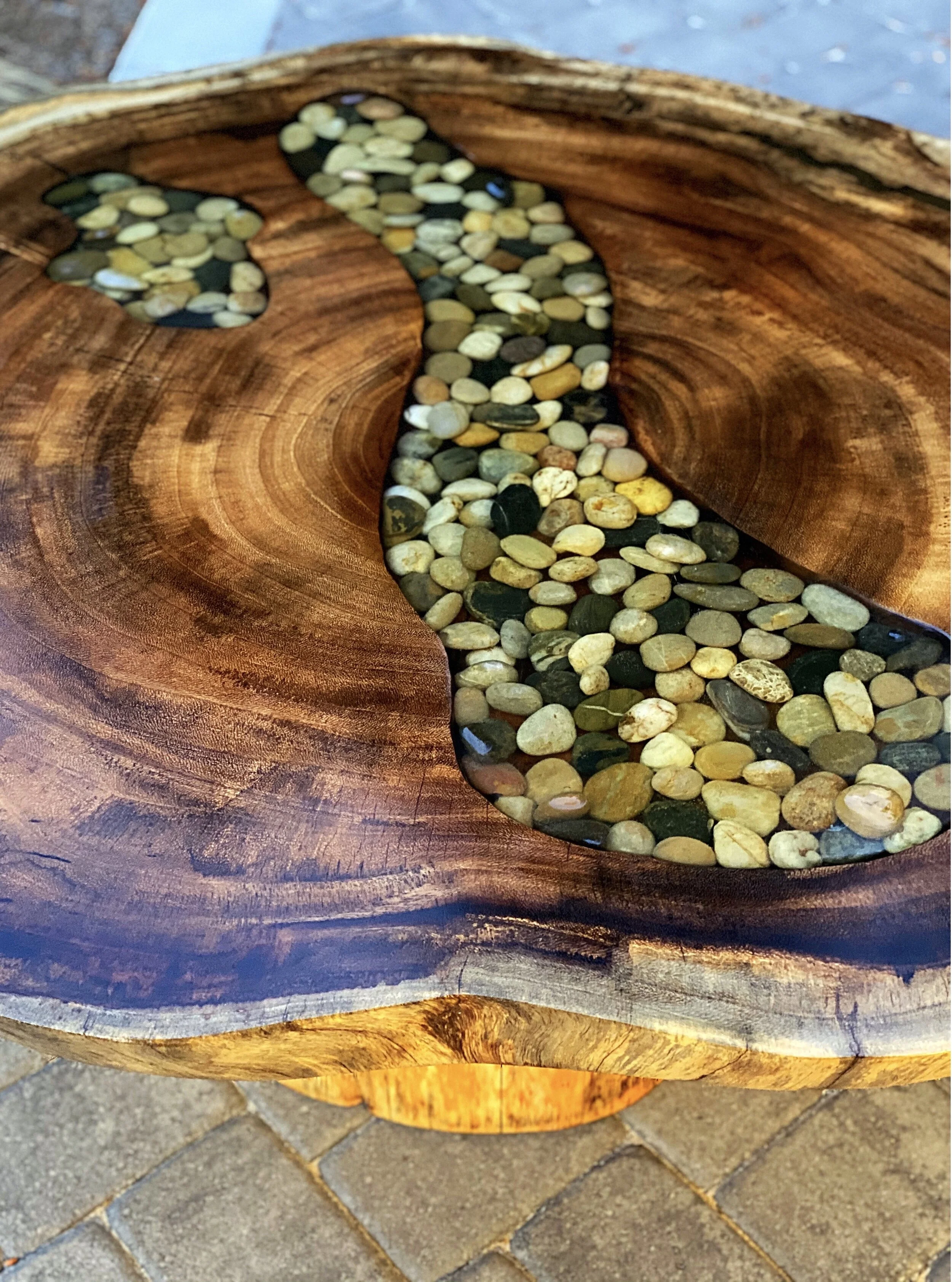 Close-up image of a wooden table with a carved out center filled with small, multicolored pebbles.