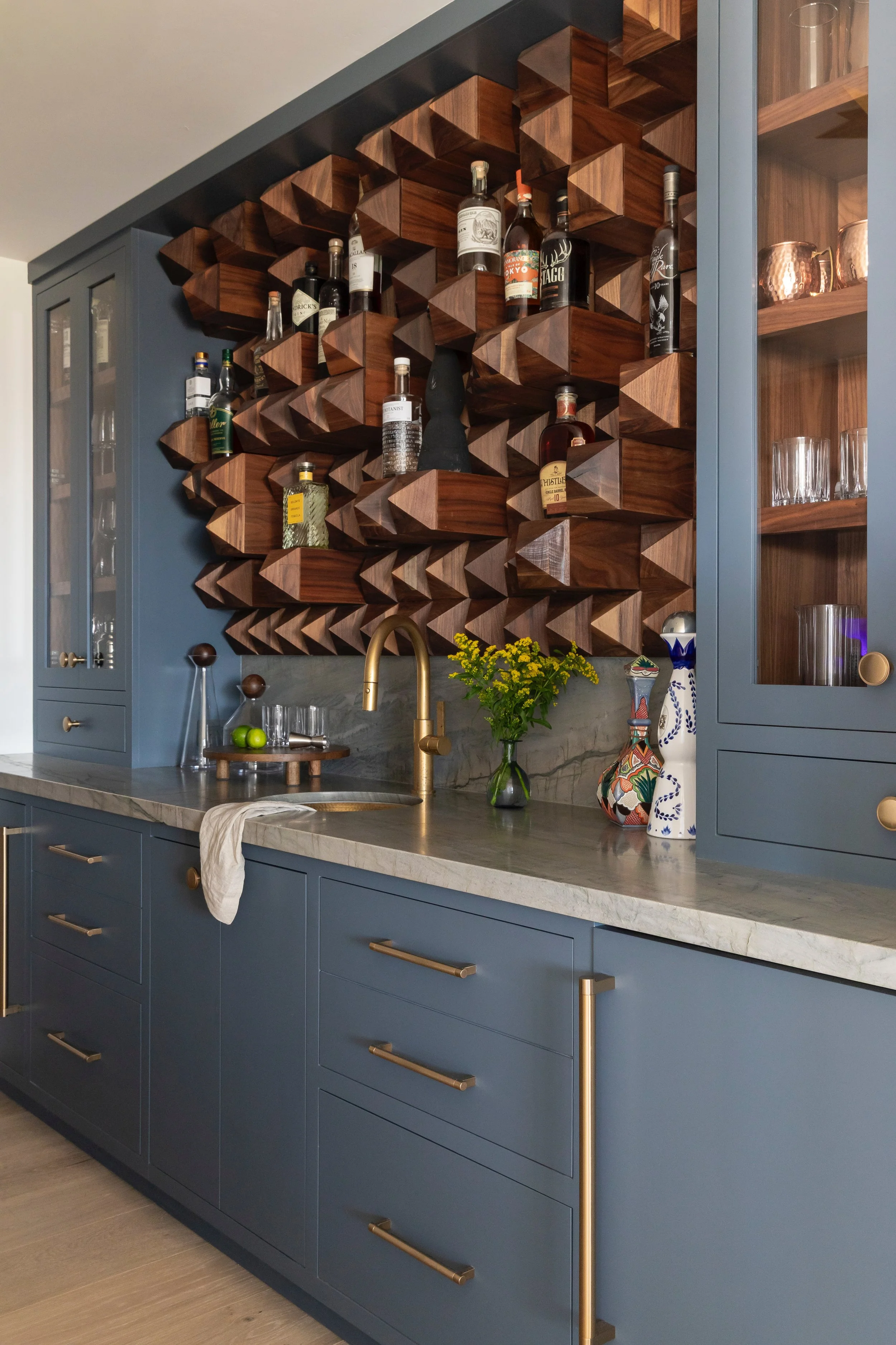 A custom solid-wood bottle display designed as a functional work of art. Precision-carved geometric forms create depth, shadow, and rhythm, transforming a spirits collection into an architectural focal point. Handcrafted from richly toned hardwood, t