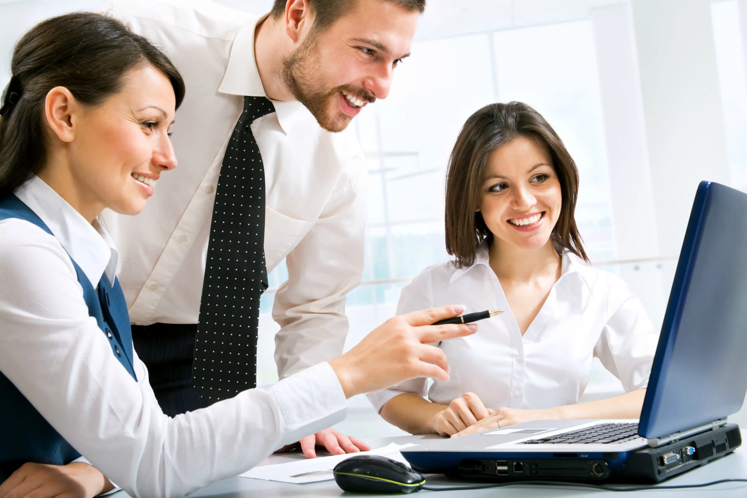 Three happy employees looking at a laptop as they receive online training