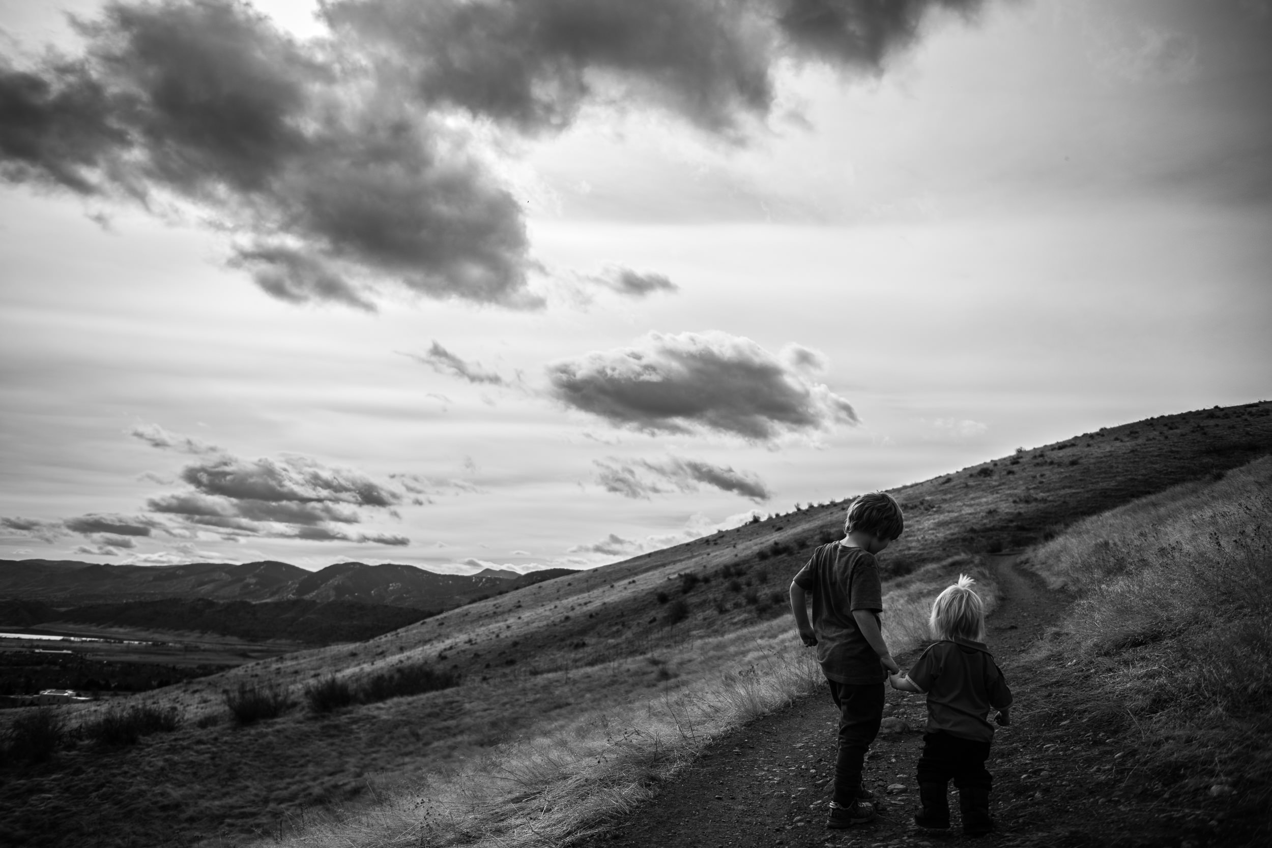 Blog - Molly Rees Photo - Black and White Documentary Childhood Photography - children holding hands on green mountain hiking trail in denver colorado by M. Menschel