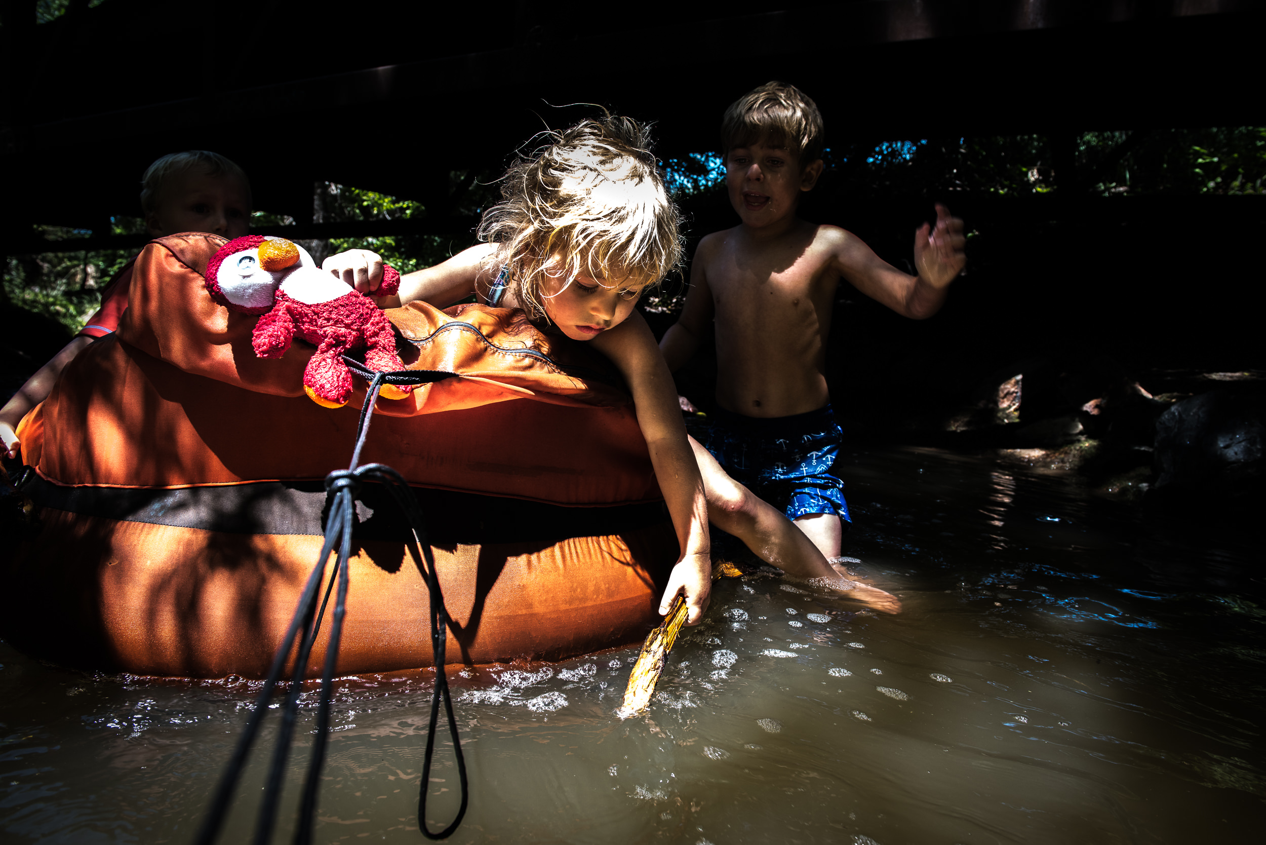 Blog - The Pen & Camera - Molly Rees Photo - Documentary Childhood Photography - children tubing in stream through woods at Belleview Park in Denver, Colorado by M. Menschel