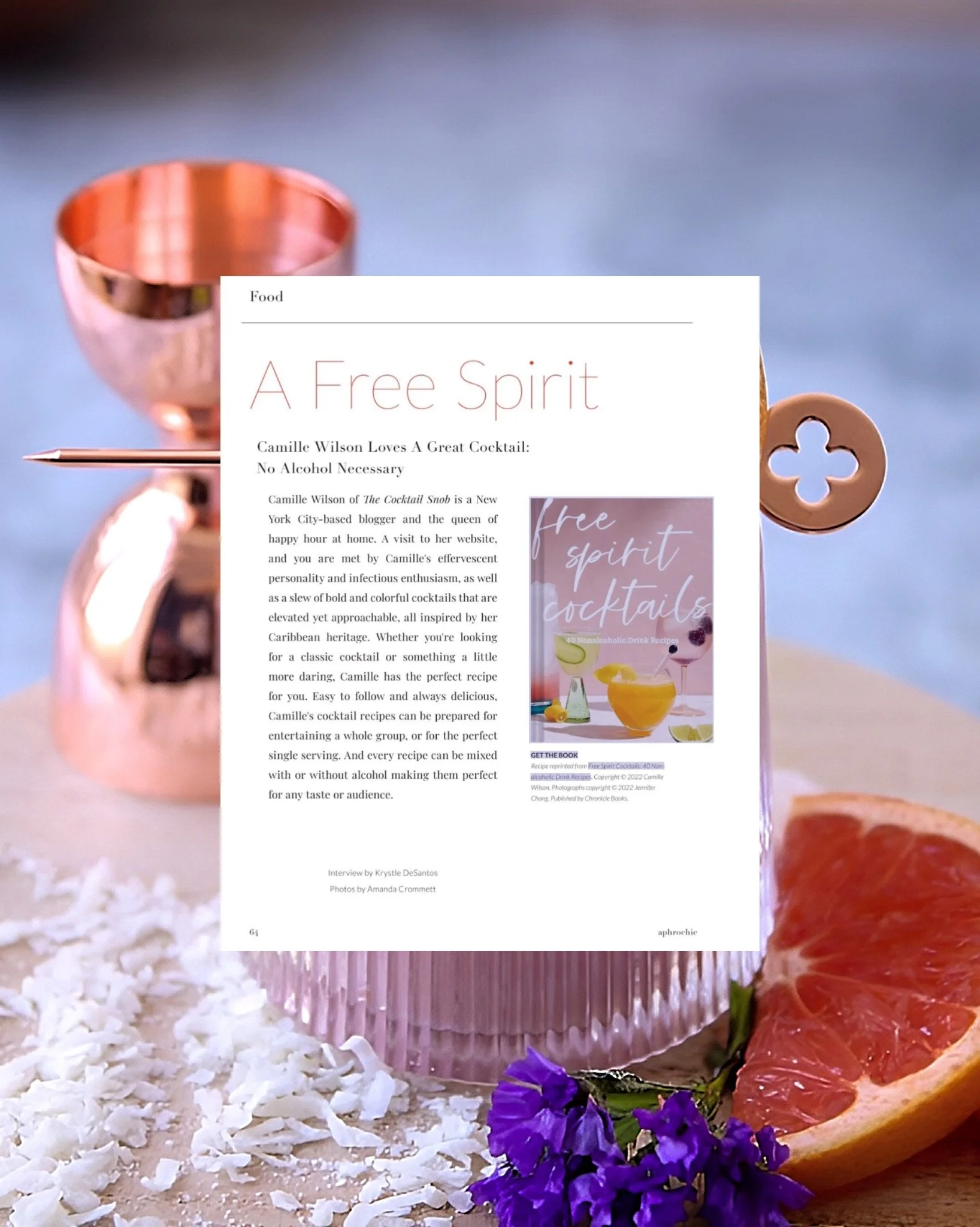 A magazine page about non-alcoholic cocktails, titled 'A Free Spirit,' displayed against a backdrop of a pink cocktail glass, a grapefruit wedge, and purple flowers, with scattered coconut flakes.