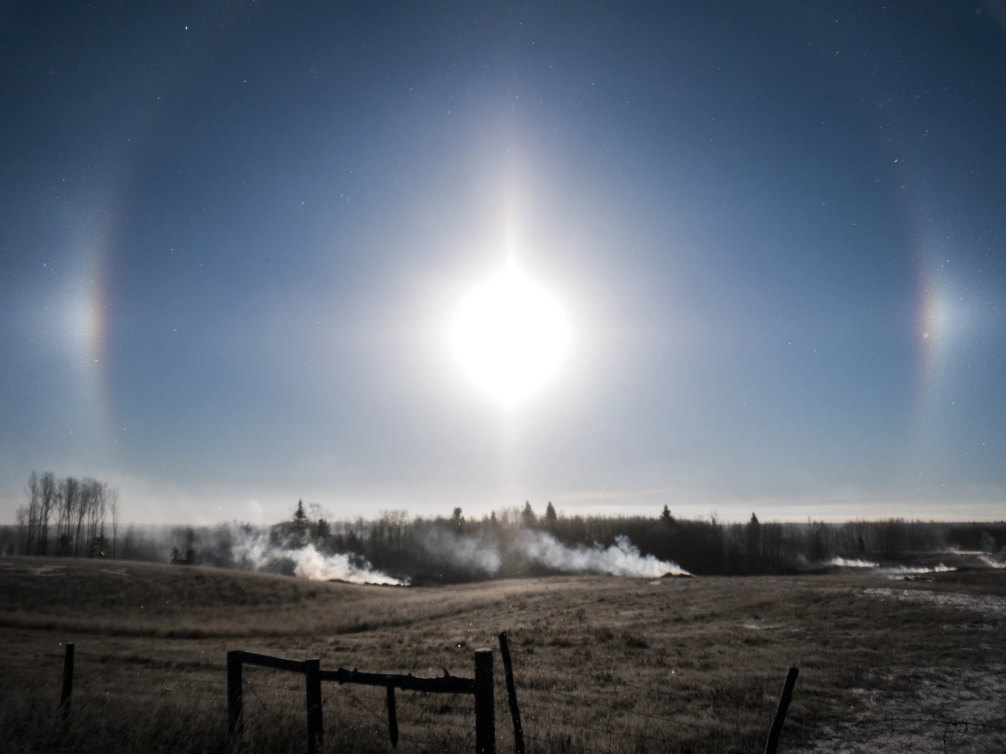 Intense snow dogs over a smokey field. Some typical parkland scenery right here, boy. 