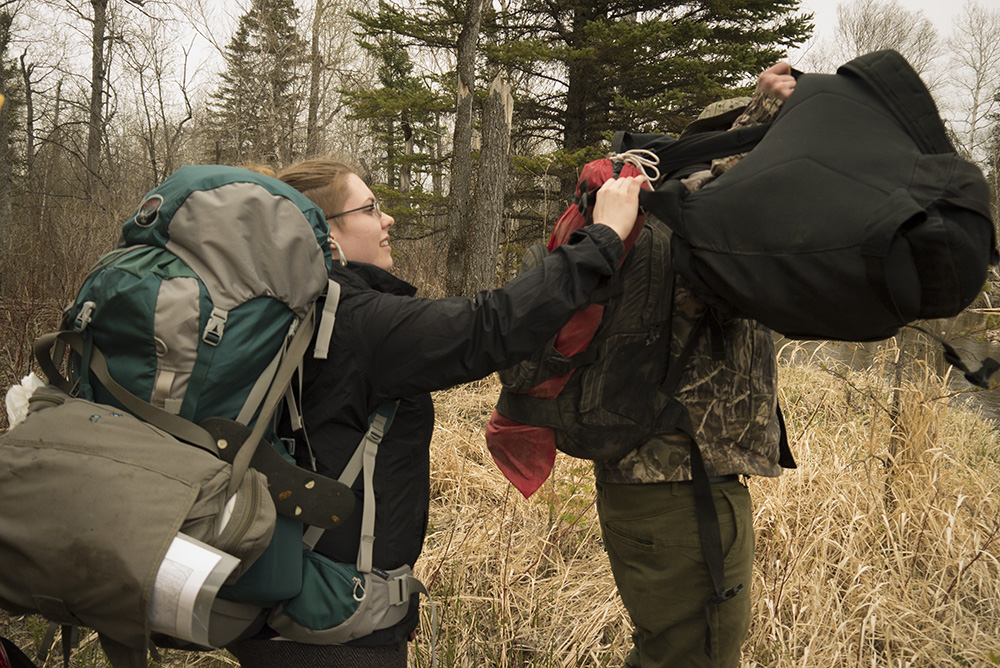 Teisha assisting Adam with his double-backpack fiasco.