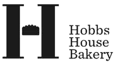 Black Signboard with white text displaying 'Hobbs House Bakery' and a stylized 'H' logo