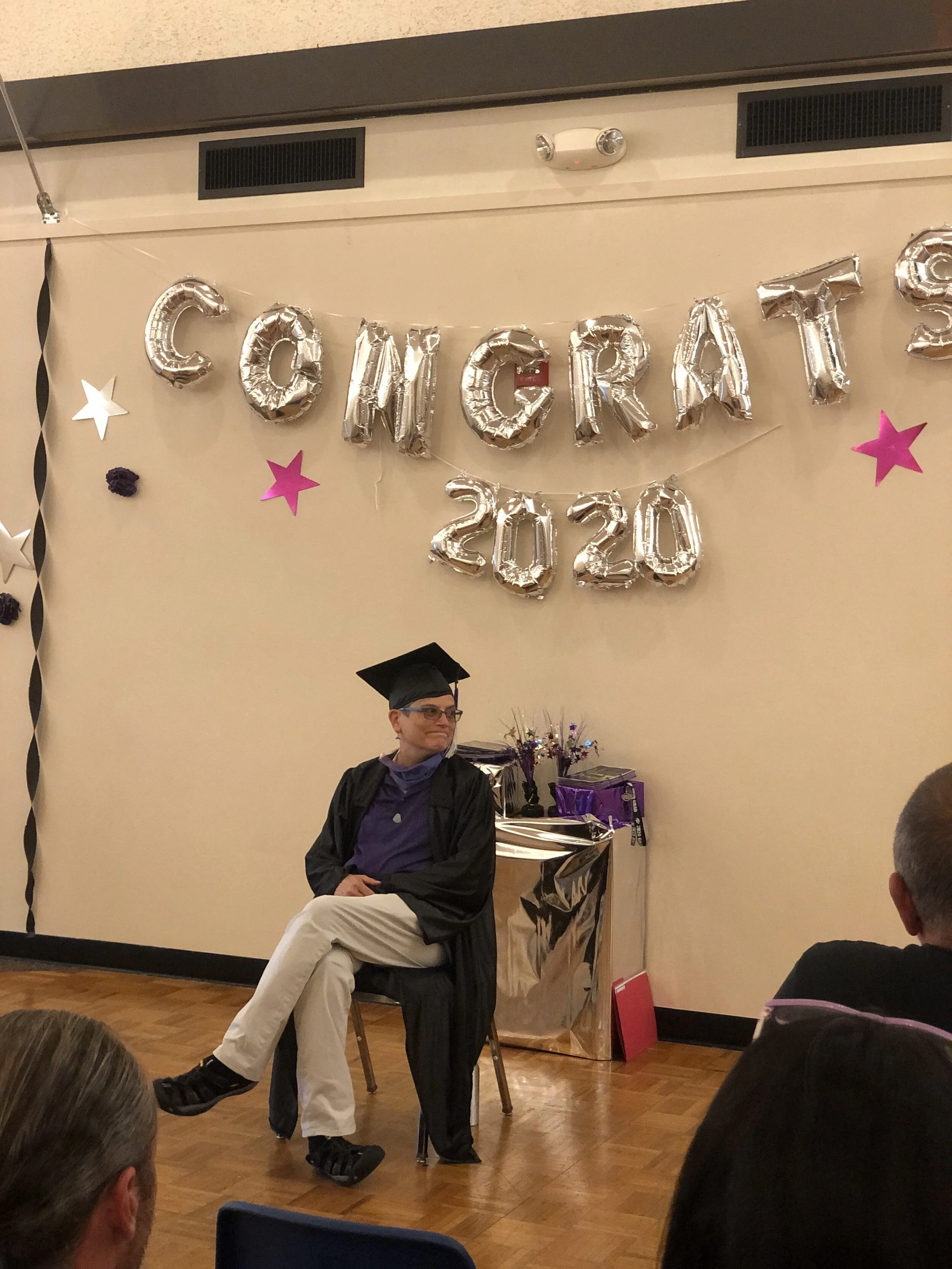 Lynda Whitener, Center Point Director, sharing words of encouragement to the graduate seated to her left.