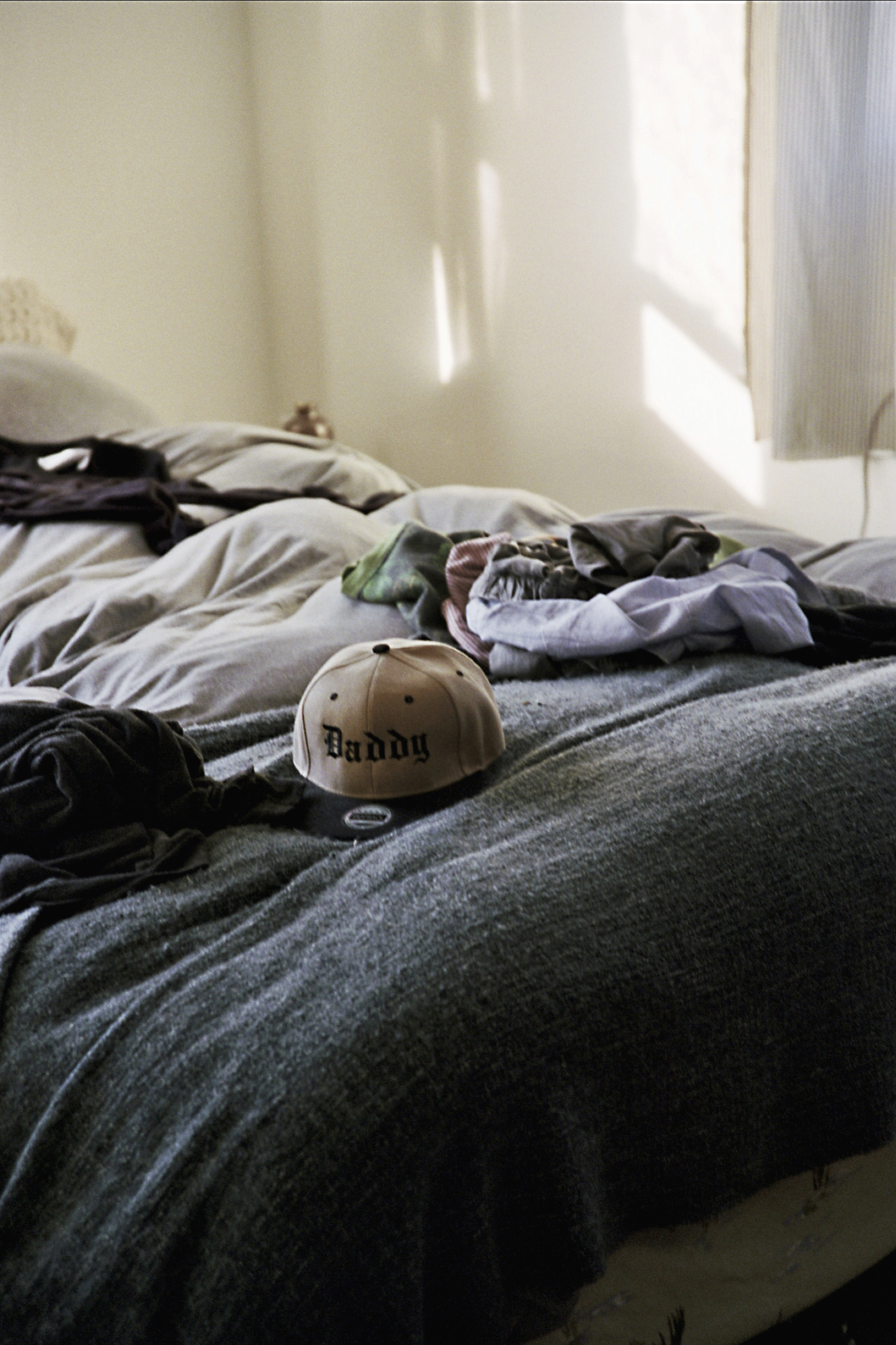 A baseball cap from a Tom of Finland Foundation dinner sits on the bed. Opposite: Ernst reclines at home.