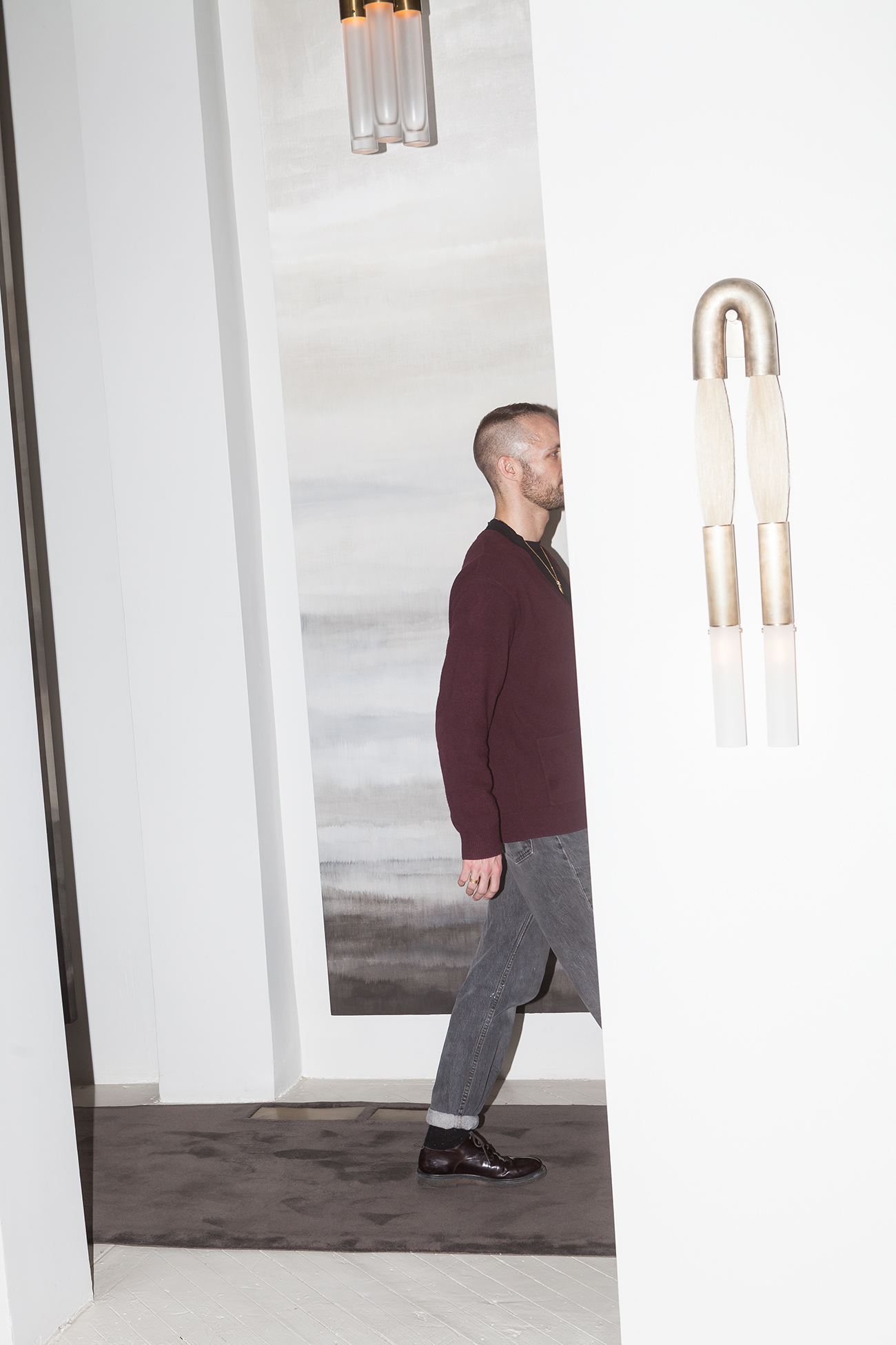 ABOVE: Anderson takes a stroll through the palatial Apparatus headquarters. OPPOSITE: A carpeted hallway featuring one the brand's now-iconic "Cloud" chandeliers.