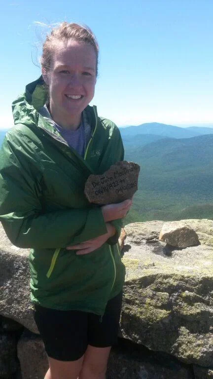 Kelsey Barklund on Mount Lafayette in New Hampshire, posing with the first memorial stone she made for her grandfather John.