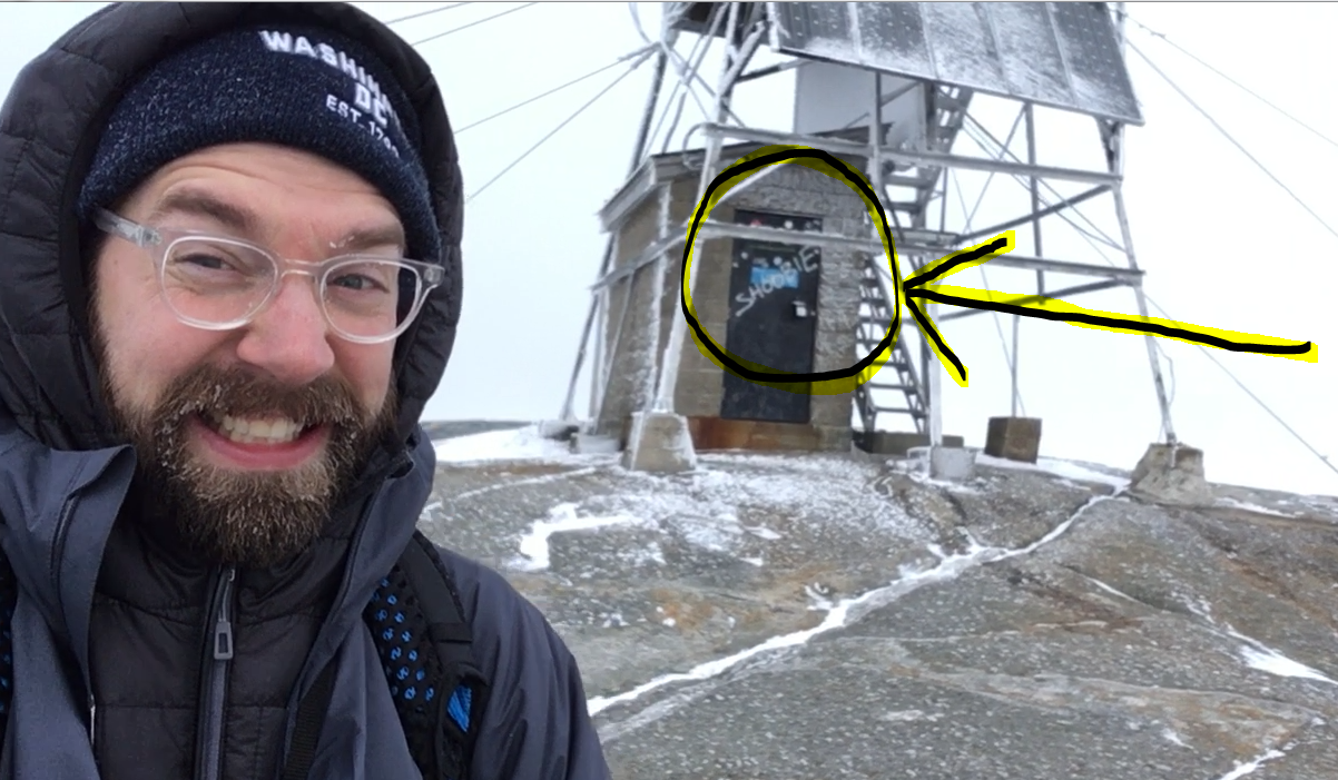 Selfie courtesy of Taylor Quimby. Directly behind the “Kind is Cool” boulder is the Mt. Cardigan fire tower, complete with graffiti.