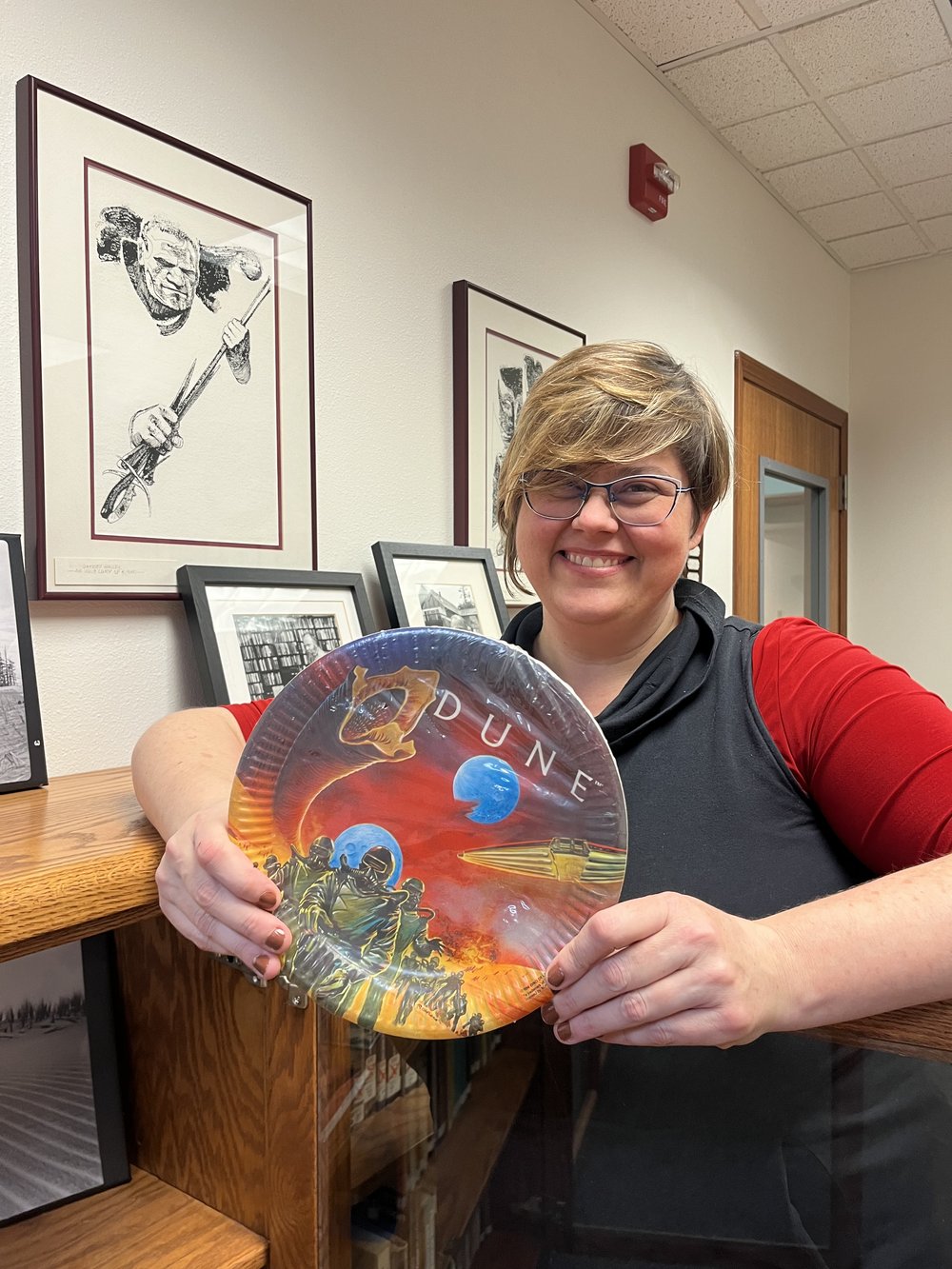  Meg Spencer, library director of the Siuslaw Public Library in Florence, Oregon, holding a piece of “Dune” memorabilia. Photo by Justine Paradis. 