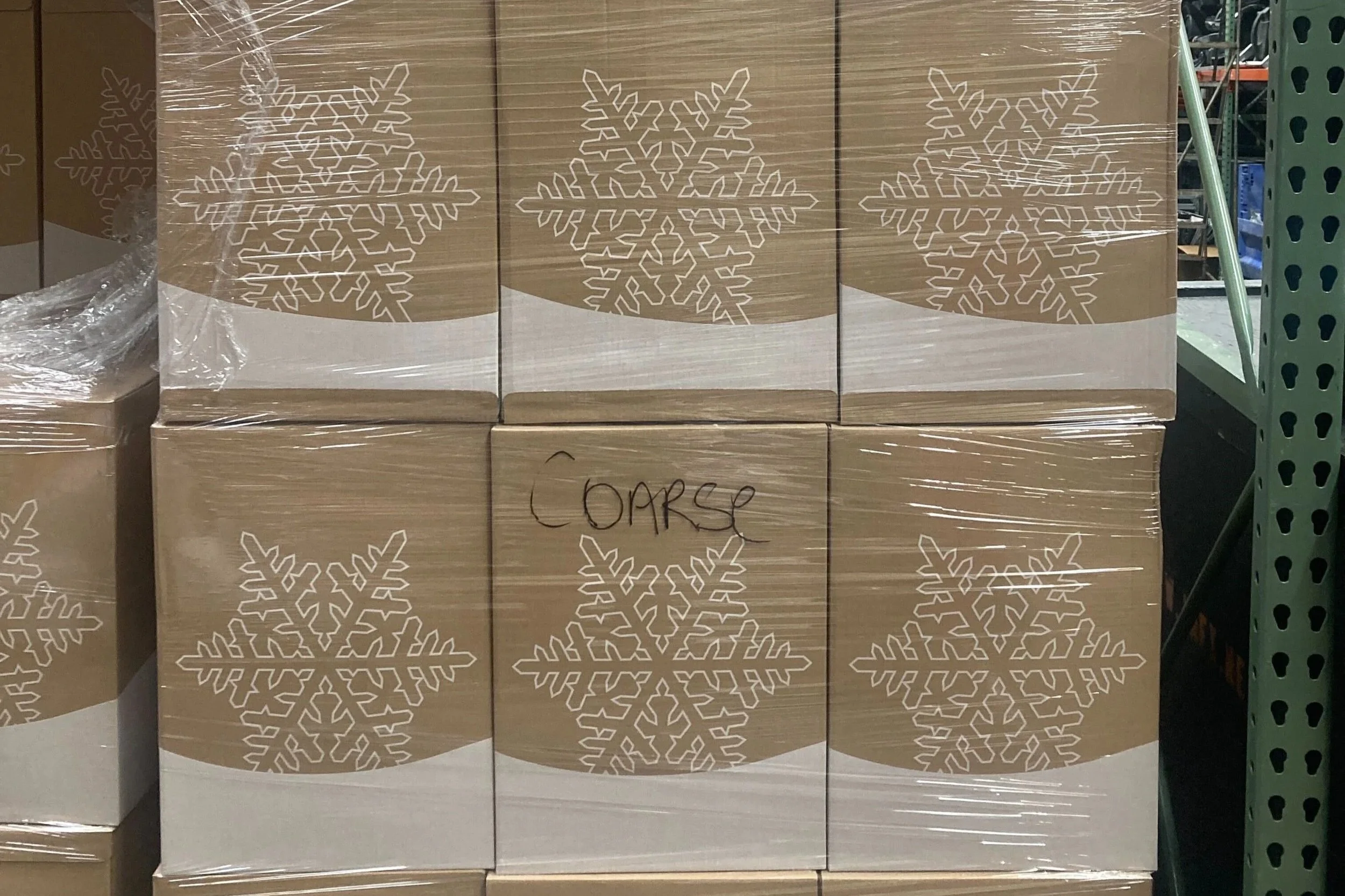 In frame, six boxes are stacked on top of each other. They each have the outline of a snowflake on their front. One of them reads "Coarse" in Sharpie.