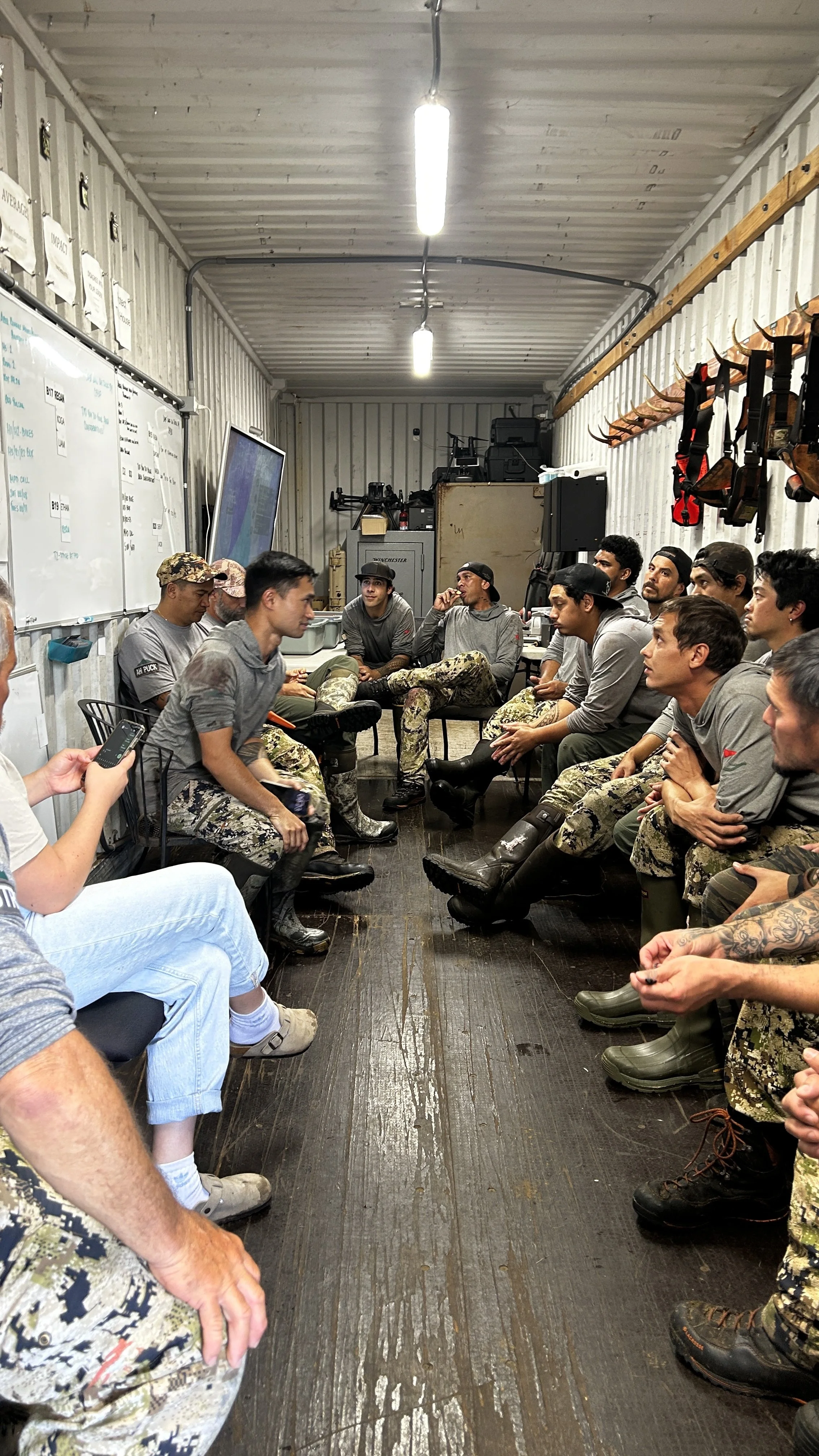 Group of men sitting in lit trailer.