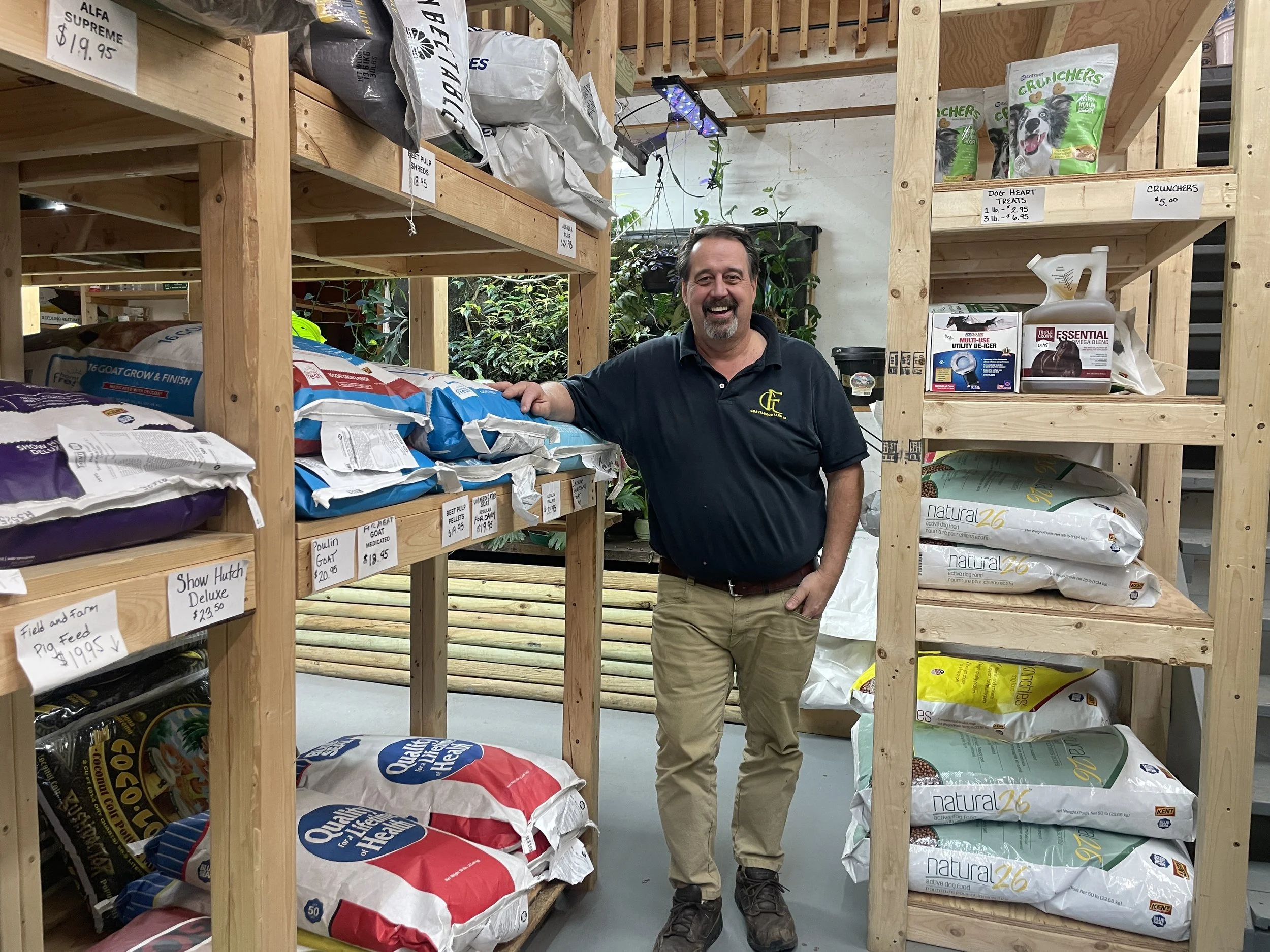 A middle-aged man stands between rows of marijuana growing supplies.
