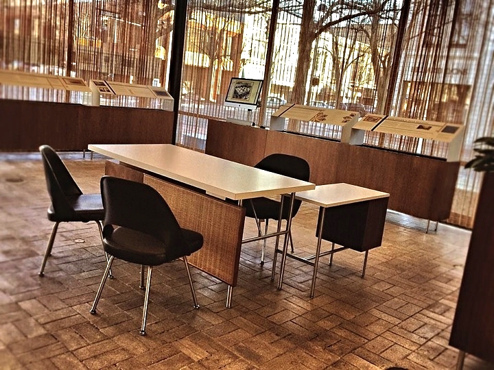 This is the interpretive area in the 1954 Eero Saarinen-designed bank building, which is now the Irwin Conference Center. The space was created to give the new user group a sense of the important history of design encapsulated in the space. This project was managed by Art Strategies and created by a sub-consultant, Venn Integration. The desk and chairs reflect the original 1954 banker’s furniture. The planters to the back were re-used to hold the exhibits and a screen that is scrolling through historic images and plays a video we produced with interviews by Will Miller and Kevin Roche.