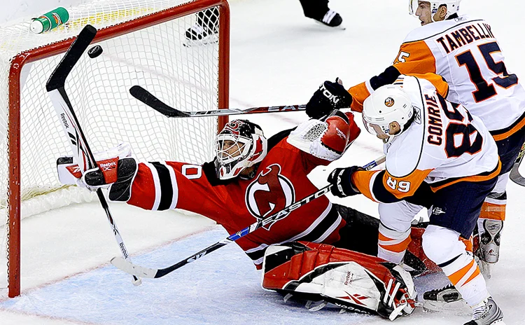 New Jersey Devils' Martin Brodeur makes an amazing diving save with only 12 seconds left in the game under pressure from Mike Comrie and Jeff Tambellini of the New York Islanders. Devils won 2-1. (Photo Credit: Saed Hindash)