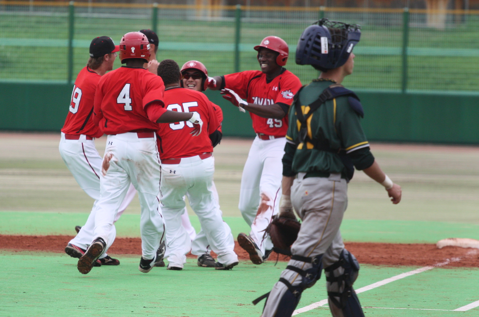 Canadian teammates mob Royce Ando (Mississauga, Ont.) after his walk-off single against South Africa.