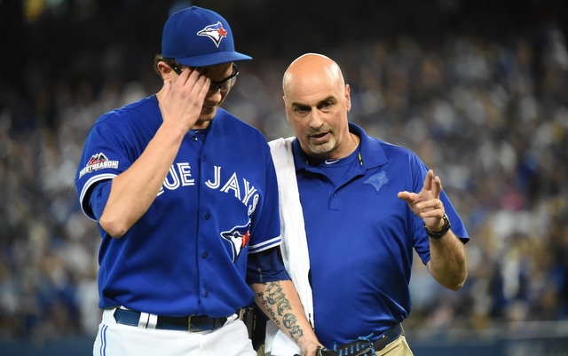 RP Brett Cecil is walked off the field by Blue Jays trainer George Poulas after tearing his calf in the eighth inning. 