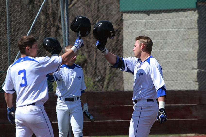 Matt Lloyd, right, of Iowa Western clanks helmets with his teammates after scoring.