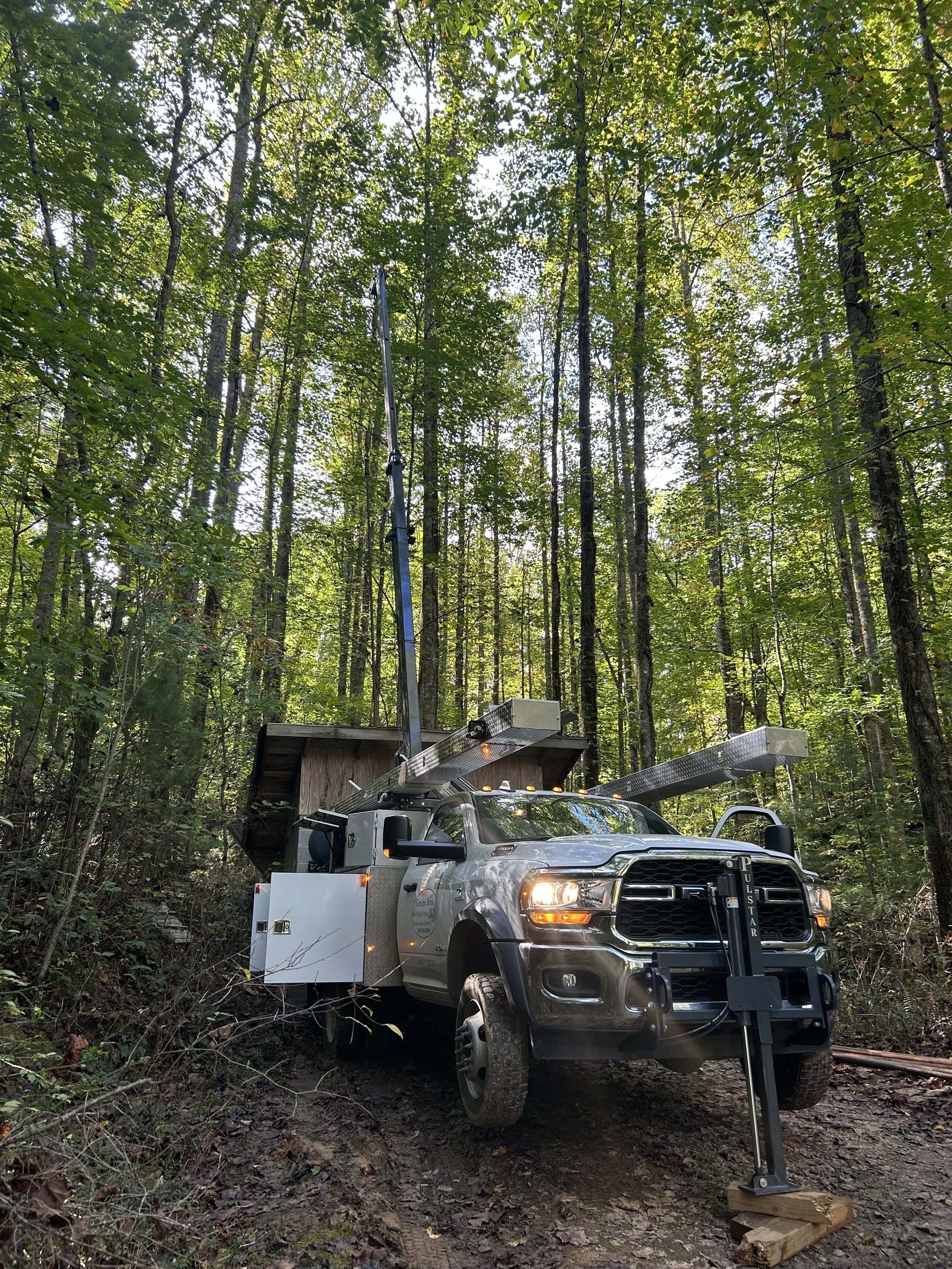 White truck in green woods installing well pump system