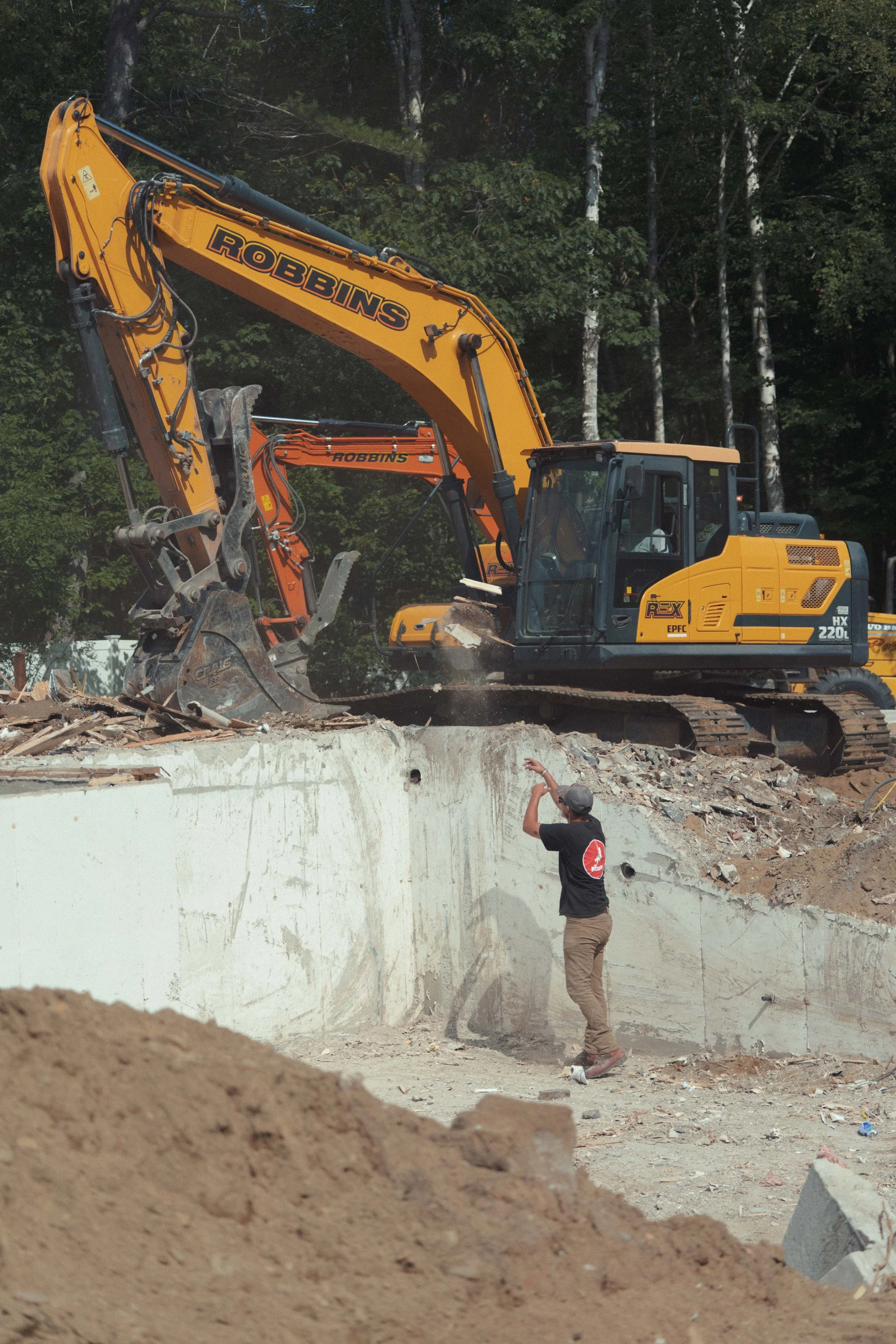 man directing excavator moving debris