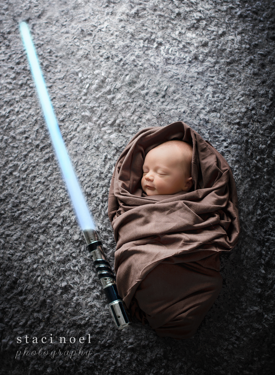 Concord, NC newborn baby boy photographed by Staci Noel Photography as a Star Wars Jedi with light saber on grey backdrop