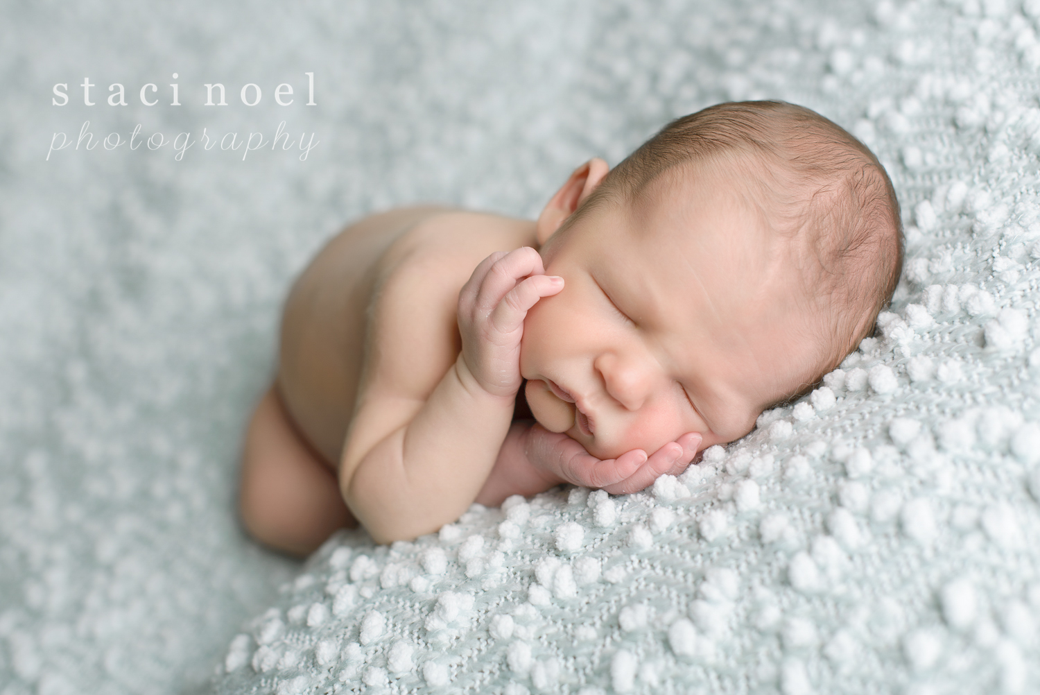 Charlotte NC newborn baby boy photographed by Staci Noel Photography sleeping with hands on cheeks on blue backdrop