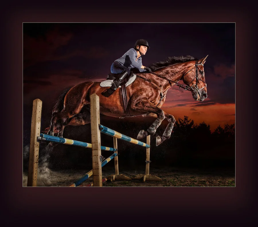 Ames high school senior Erin Lehman jumps her competition horse at dusk with a look of determination on her face. This strobist image accentuates the horse's muscles and shiny coat. Photographed in Ames, Iowa by Des Moines Photographer Dan McClanahan. Photo was selected for the 2014 PPA Loan Collection.