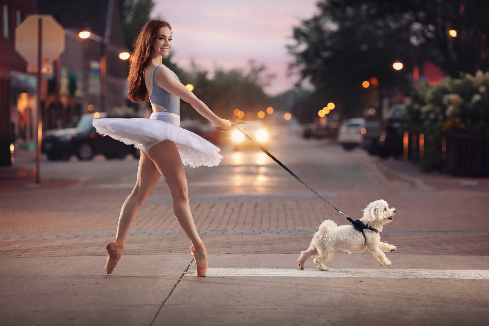Ballerina in pointe shoes taking her dog for a walk in downtown Ames, IA