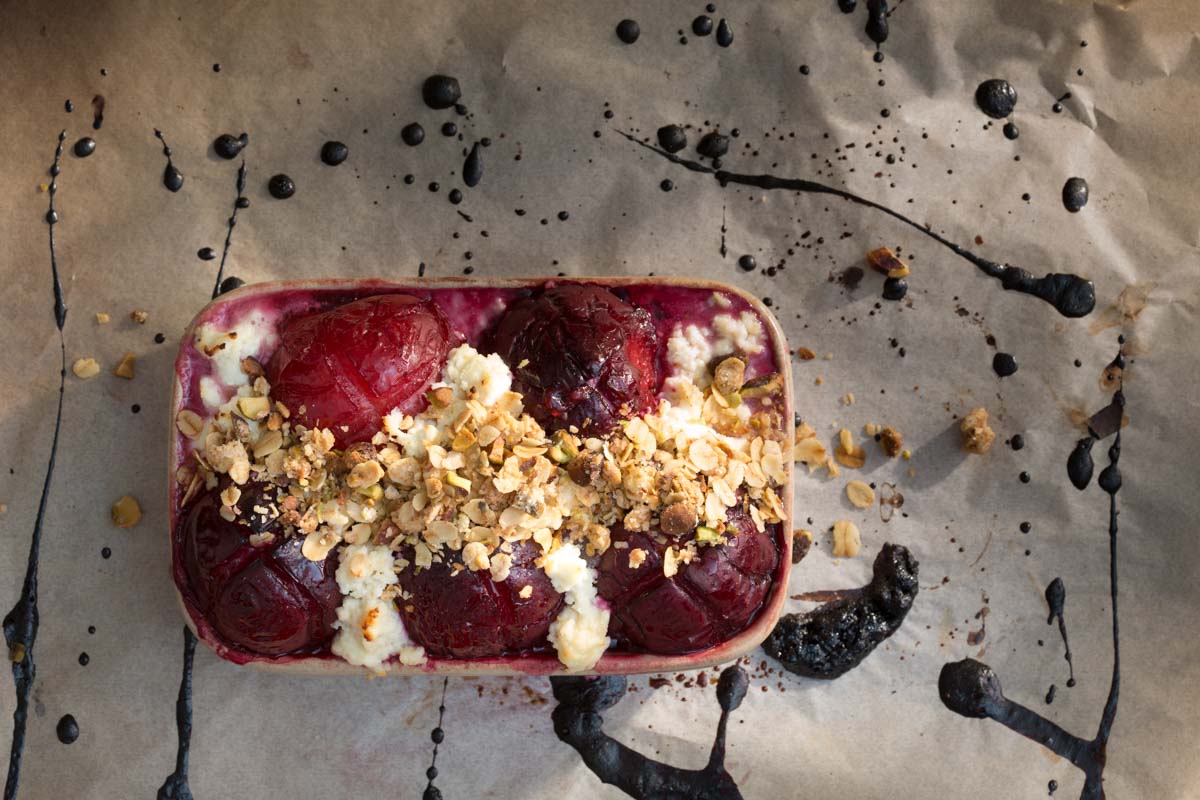Baked plumbs with honey ricotta, red wine syrup and pistachio crumble