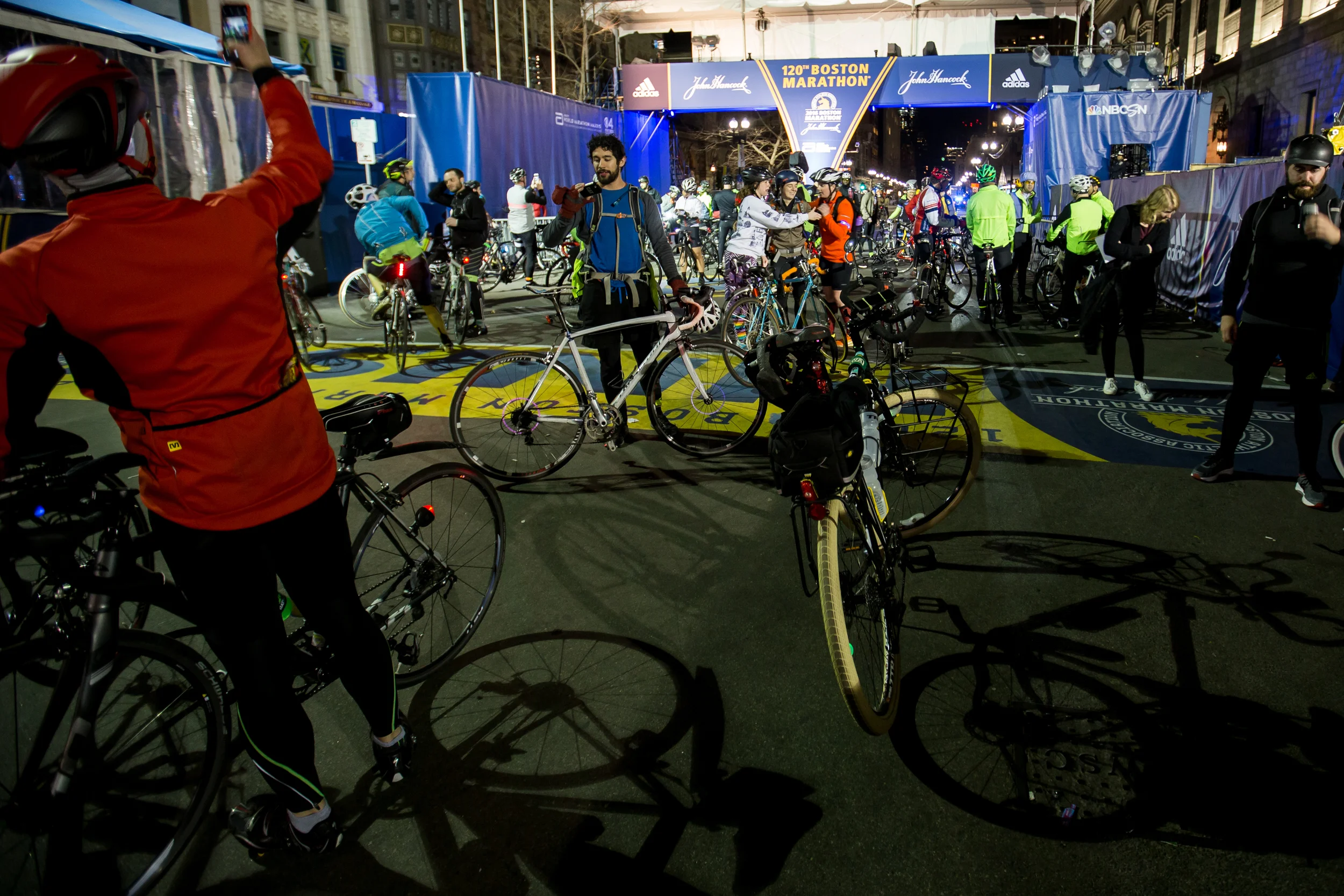 Participants rest and take photos after completing the Midnight Marathon Bike Ride, which begins at midnight on April 18 in Hopkington, Mass., and traverses the route of the Boston Marathon.