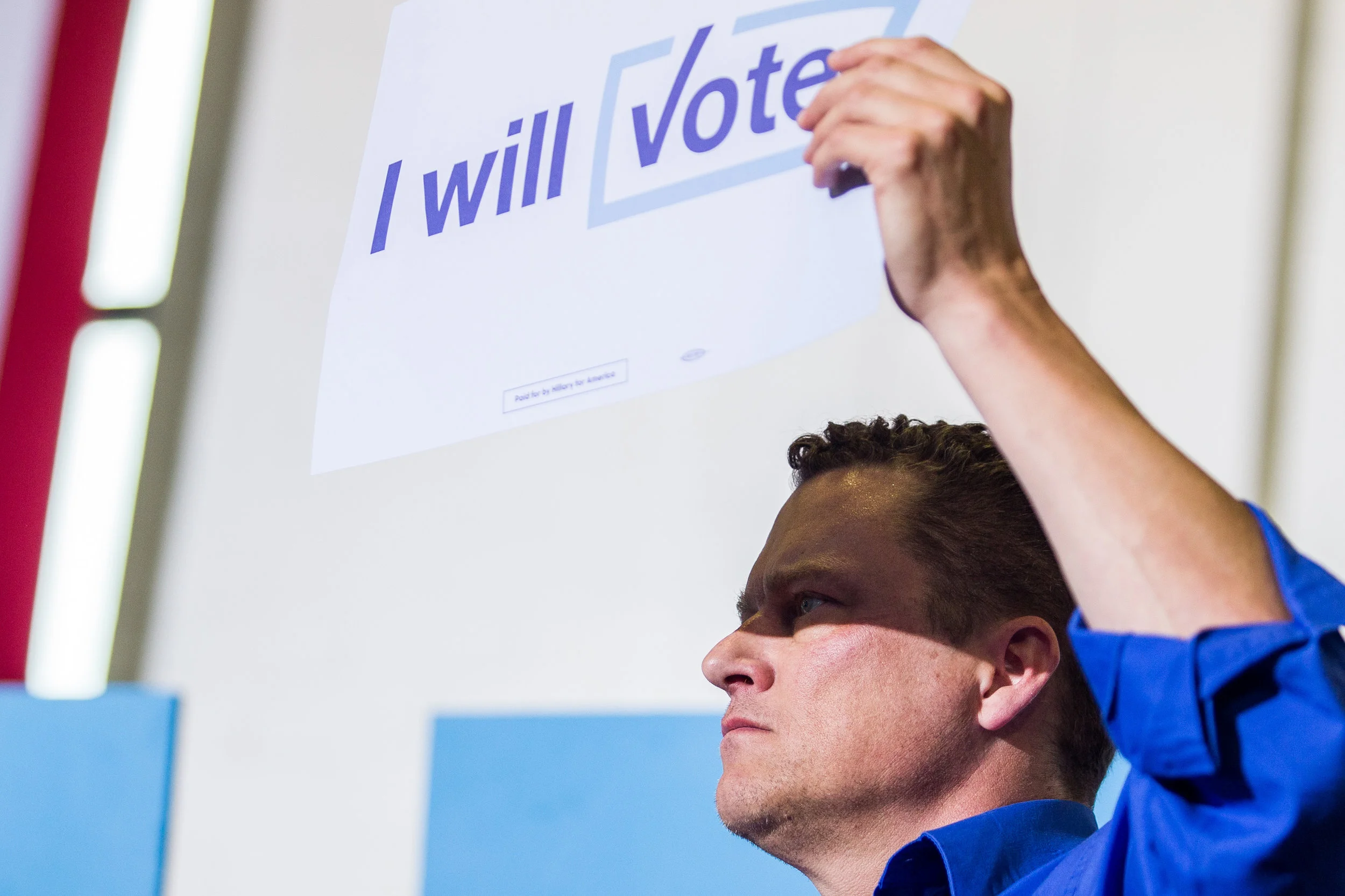 A Hillary Clinton supporter uses a sign to shield his eyes from the light at Clinton's New College Compact Event at the University of New Hampshire, Durham, New Hampshire, September 28.