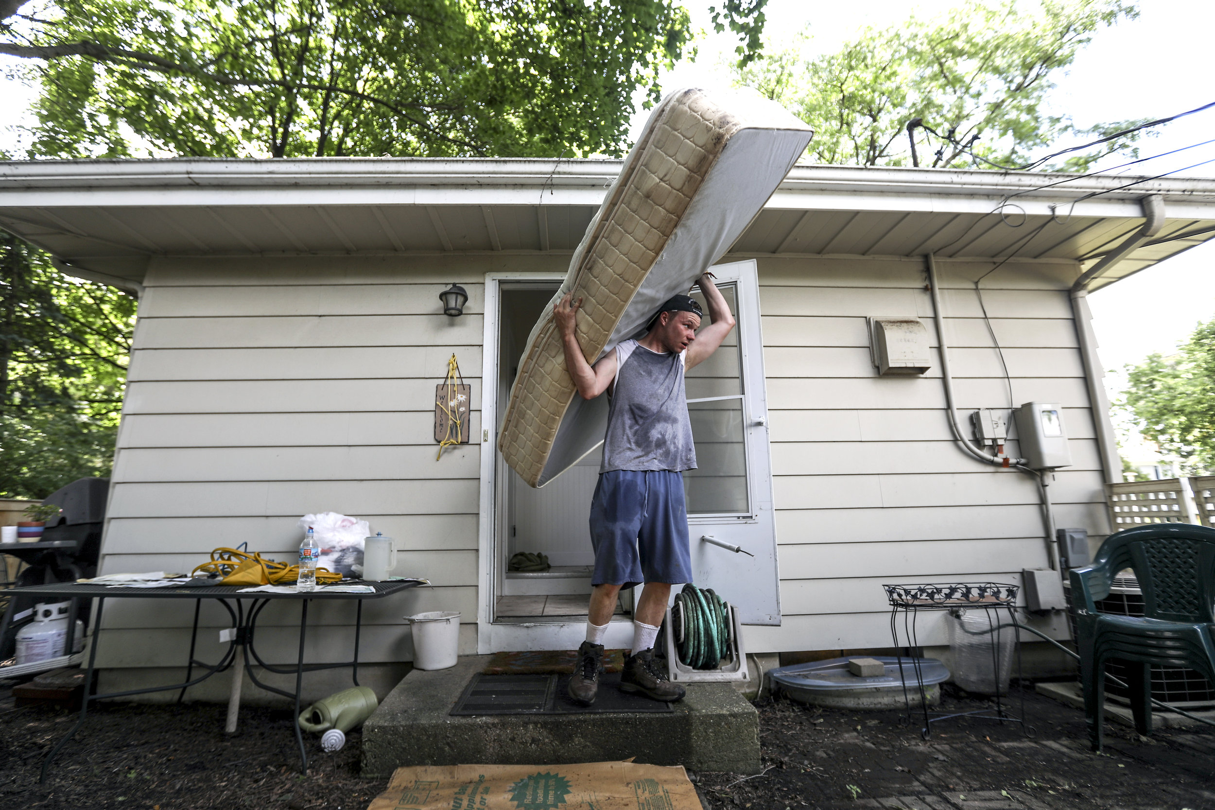 Jacob Grant removes a mattress damaged by floodwater and sewage from a flooded basement on Rockland Road in Libertyville on July 13, 2017.
