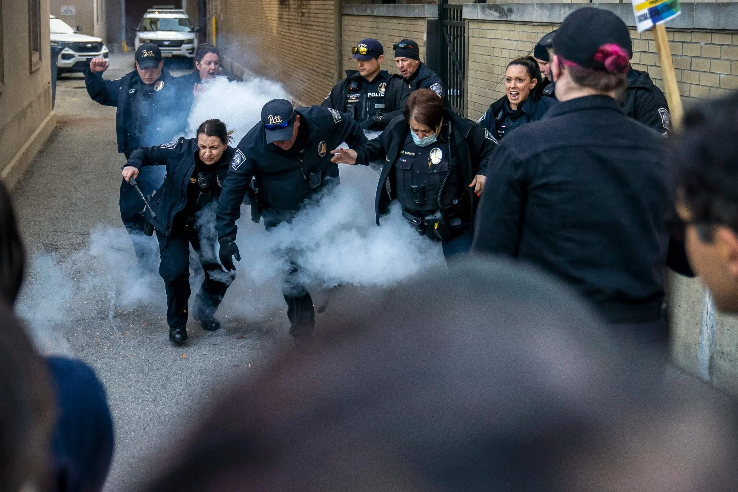  University of Pittsburgh Police officers react after a protester threw a device emitting smoke at the group of officers gathered by an entrance to the O'Hara Student Center on University Place. Demonstrators were protesting a debate called "Should T