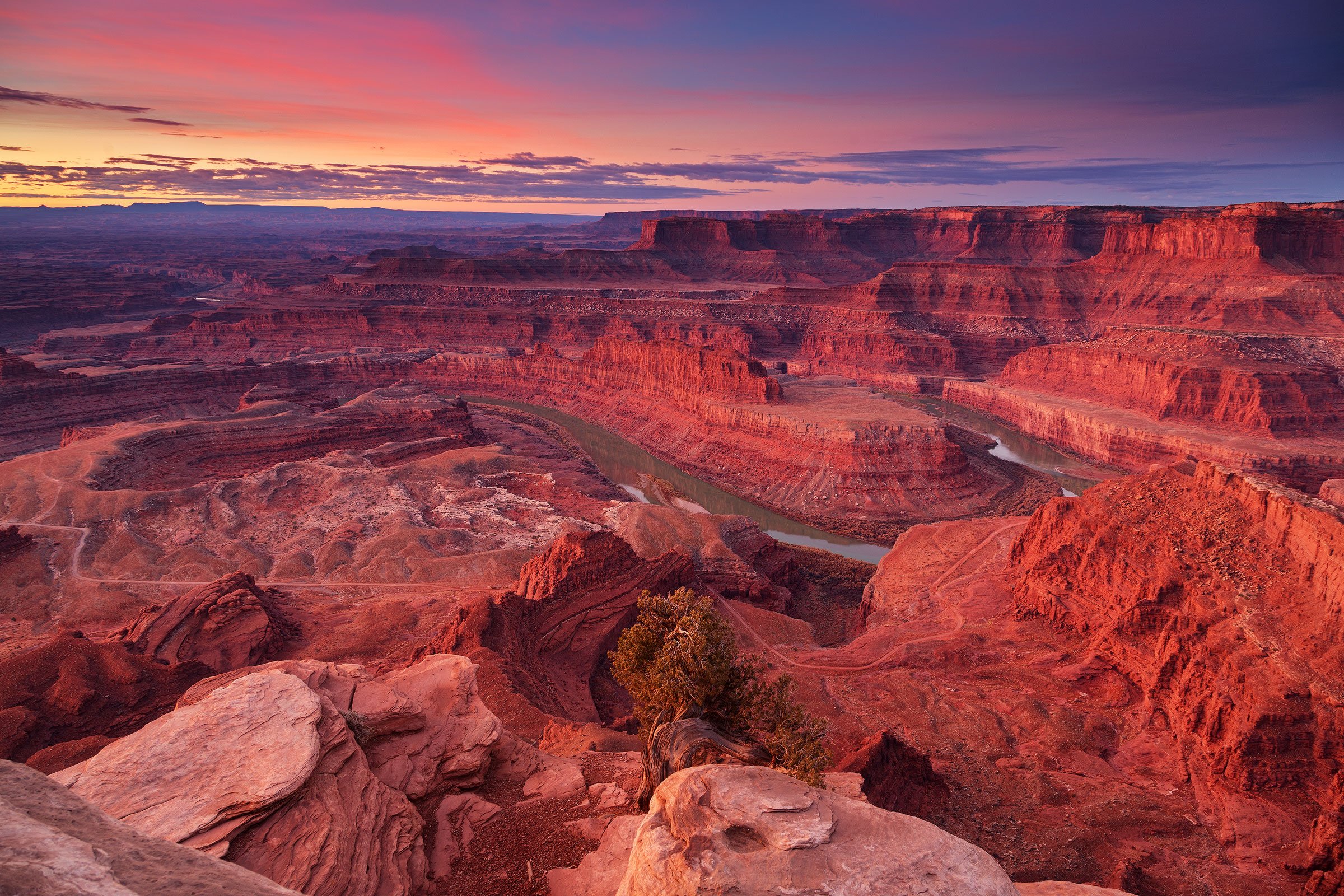 Sunrise view from Dead Horse Point State Park in Utah, with the Colorado River winding through red rock canyons under a colorful sky