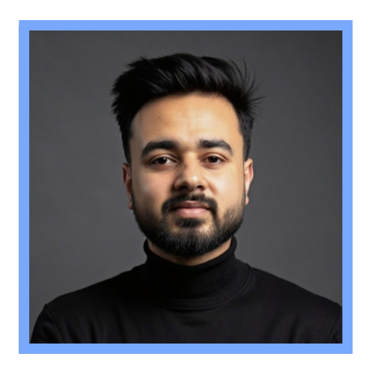 Portrait of a man with dark hair and a beard, wearing a black turtleneck sweater, against a grey background.