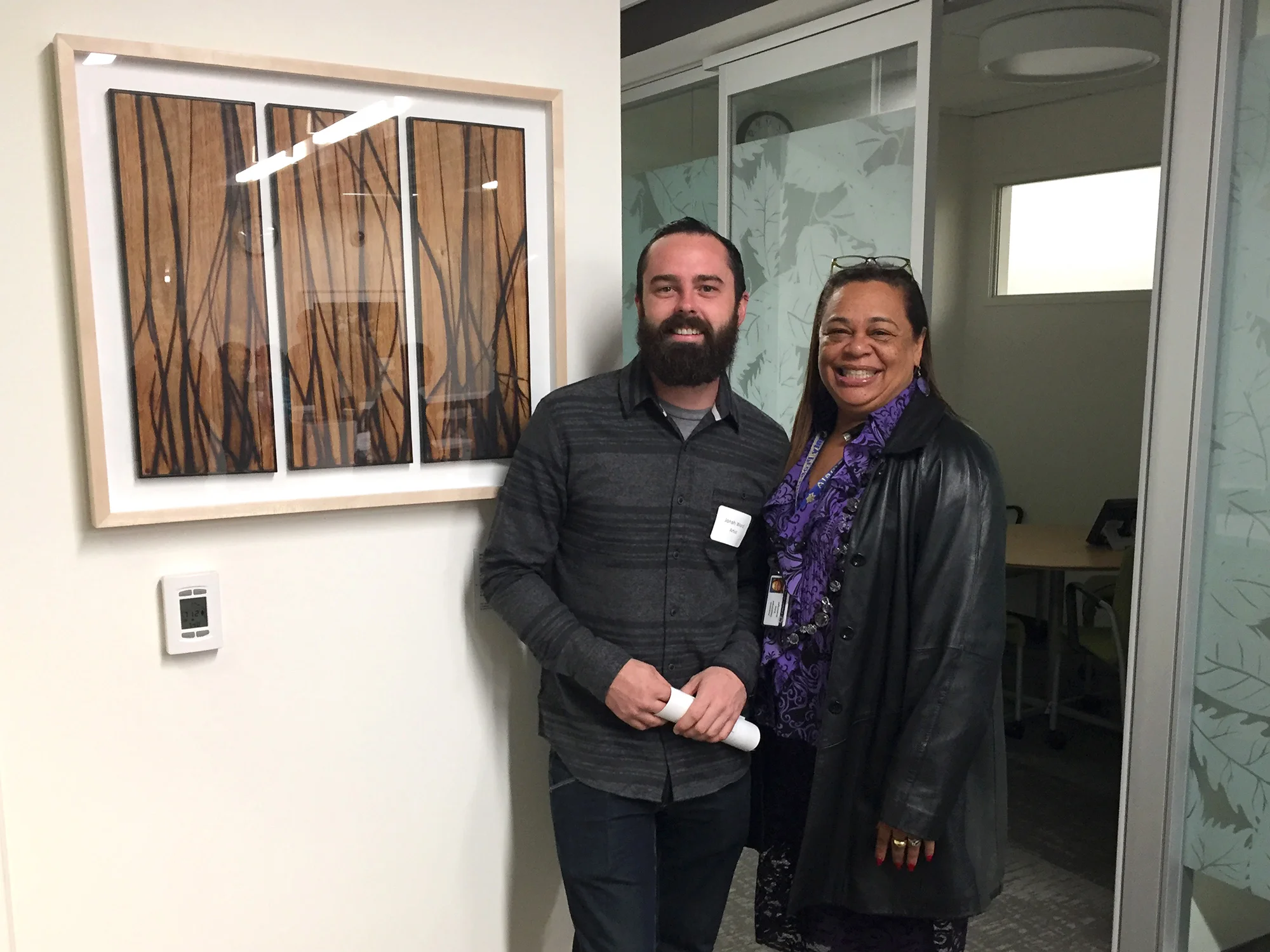 Jonah Ward with Edna Boatwright, an Artwork Selection Committee Member, standing next to one of his glass burned panels selected for the building.
