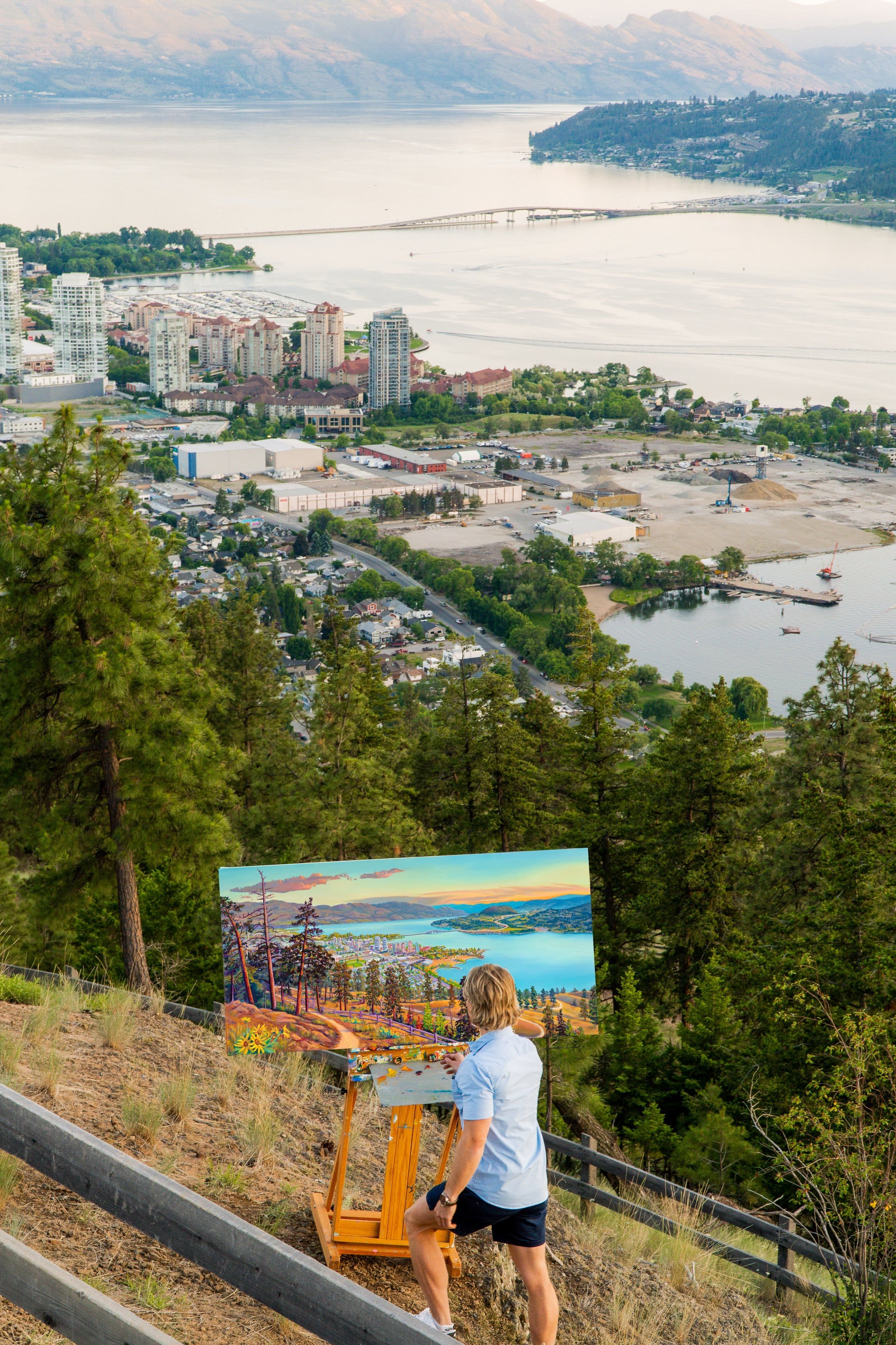 Kelowna artist plein air painting on top of Knox Mountain at the top of the Apex trail at sunset overlooking Downtown Kelowna and Okanagan Lake in British Columbia