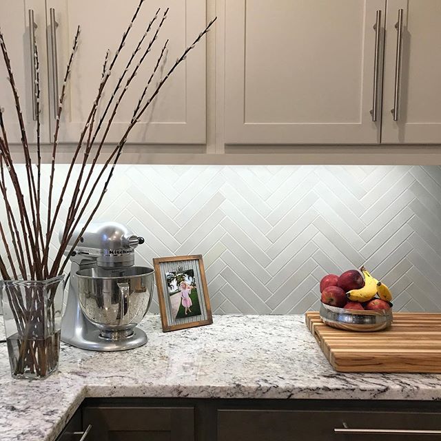 Kitchen backsplash installed! Herringbone pattern and color variation in the grey tile ties the white upper and grey lower cabinets together. Love the cutting large format teak board #americastestkitchen .
.
#BestTile #tiledesign #kitchen
